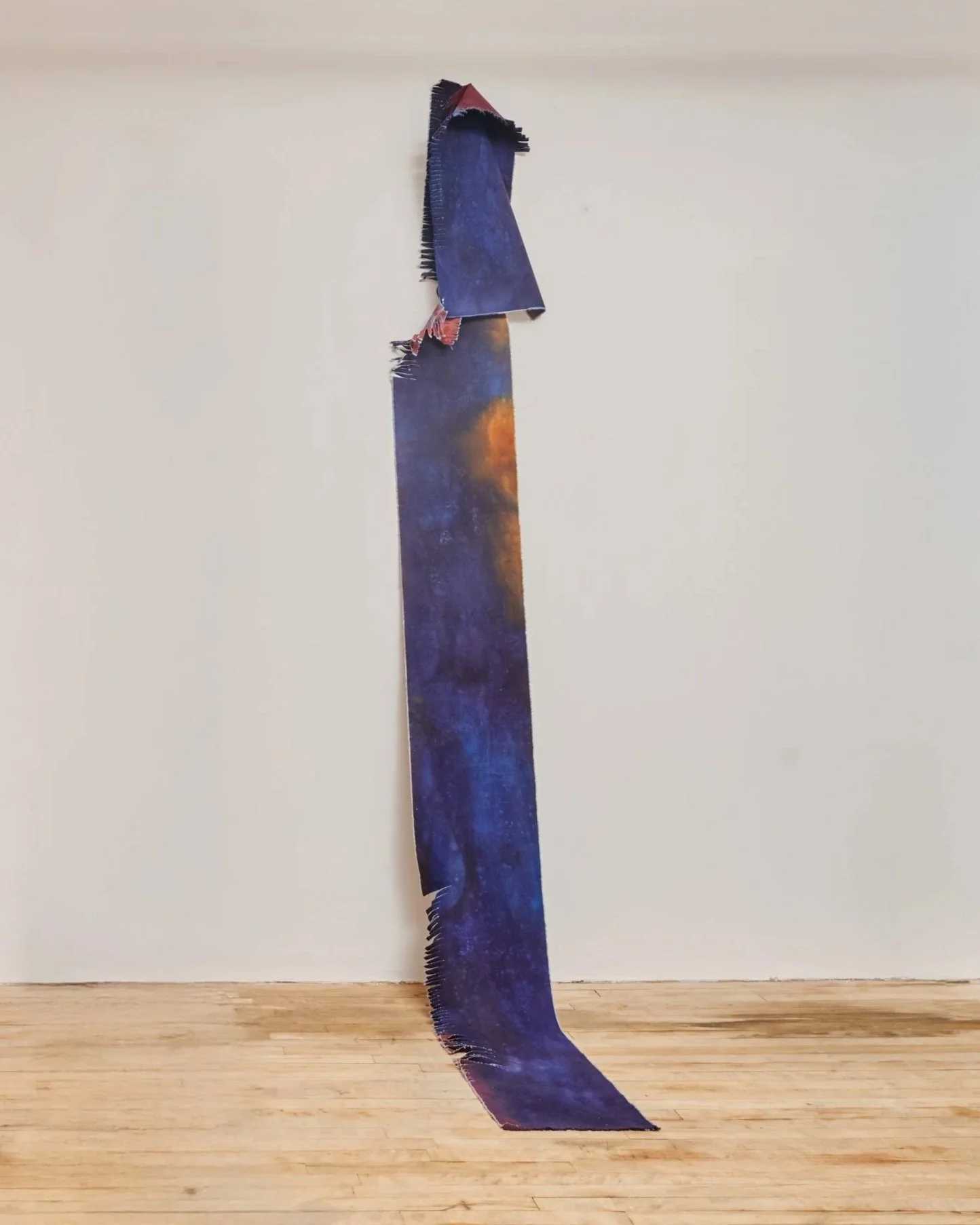 Long, narrow artwork with a galaxy-inspired design featuring dark blue and orange hues, hanging against a white wall. Vaughn Davis Jr.