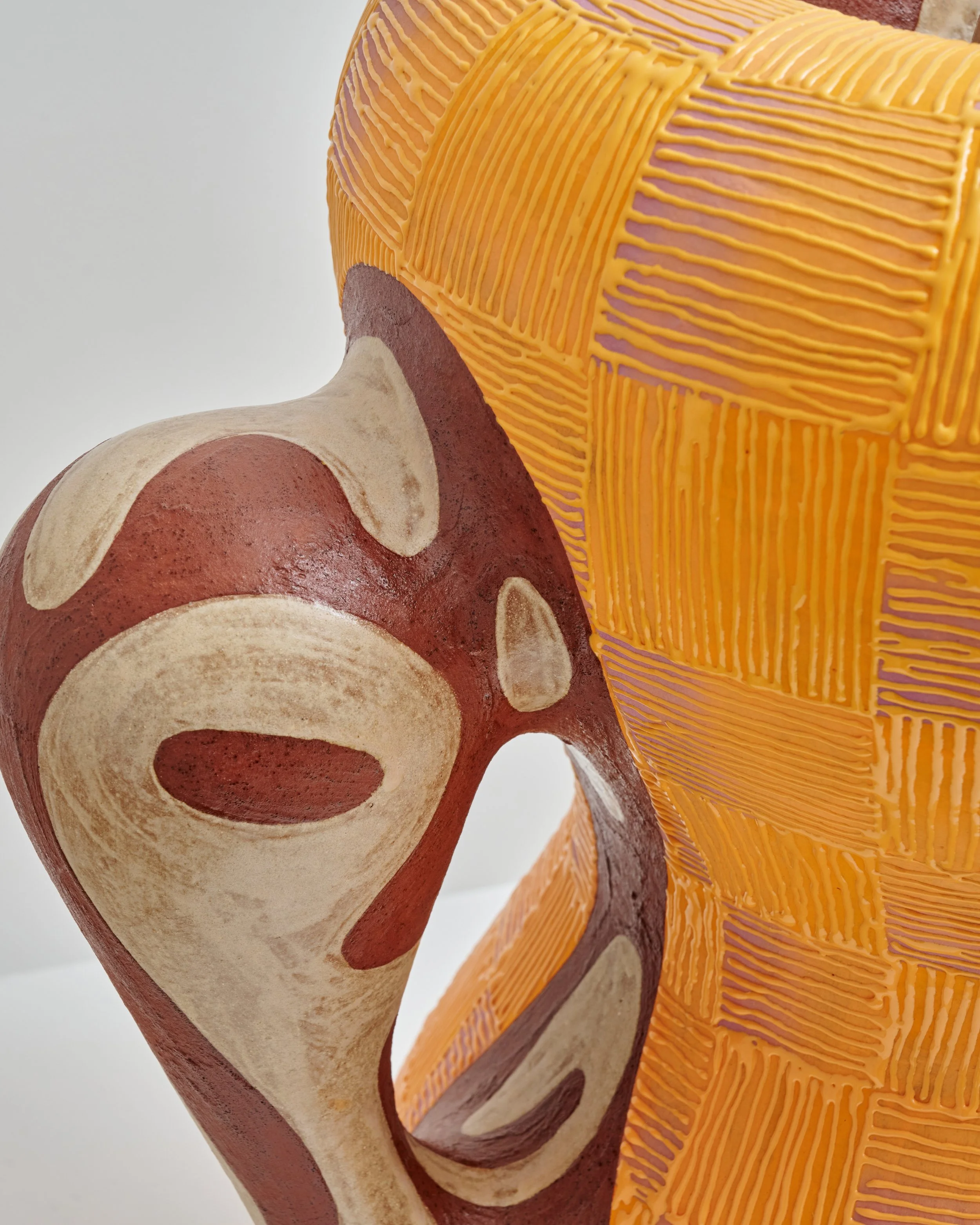 Close-up of a colorful, textured sculpture resembling a stylized animal, with orange, beige, red, and purple hues, featuring striped and circular patterns on its surface. Joël Brodovsky-Adams.