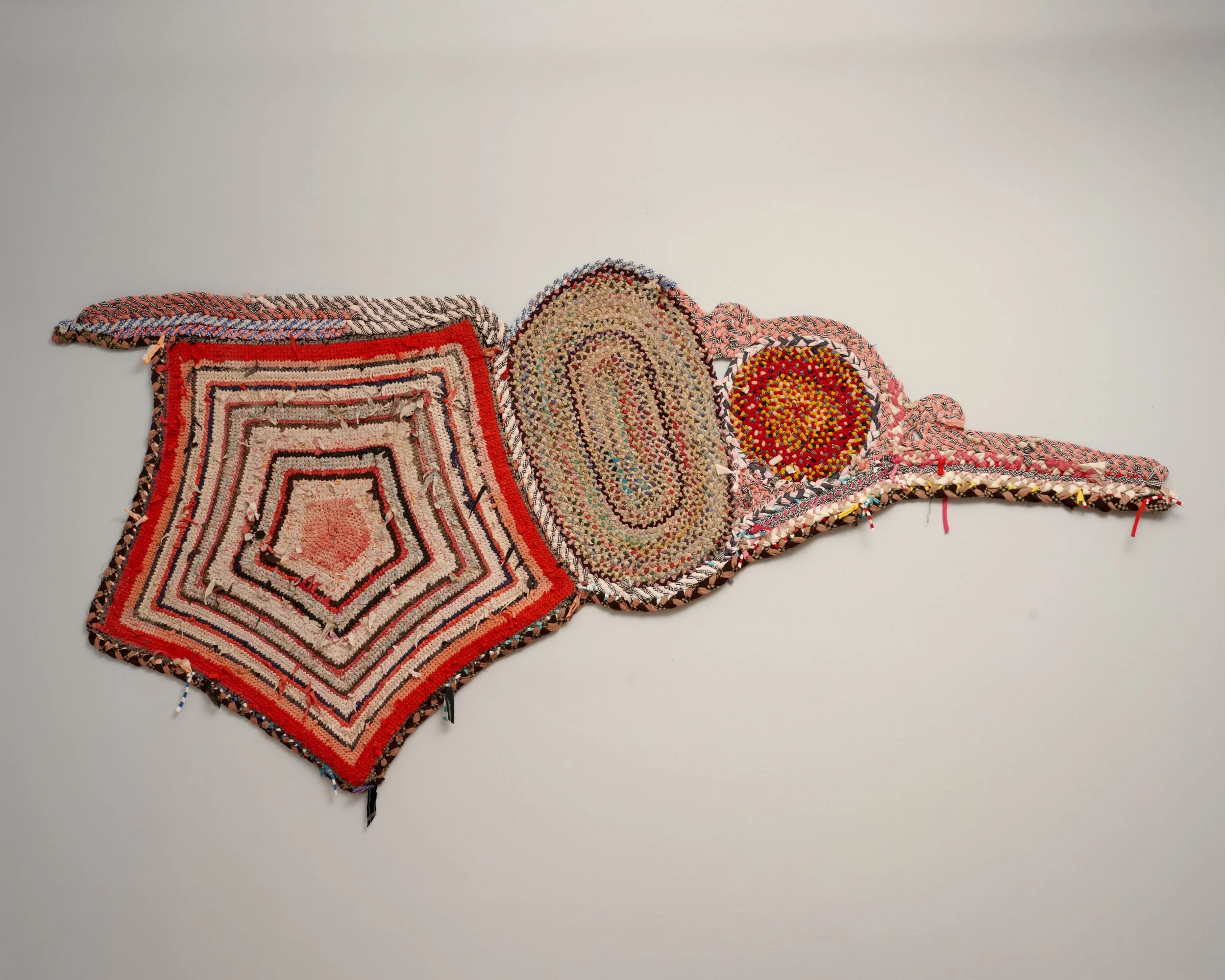 Colorful, abstract textile wall art with geometric and oval shapes, composed of various small fabric pieces and textures.