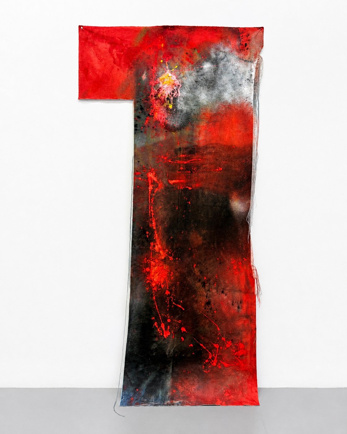 Abstract art piece with dominant red, black, gray, and white colors, featuring splashes and splatters of paint on a long fabric or canvas hanging vertically.
