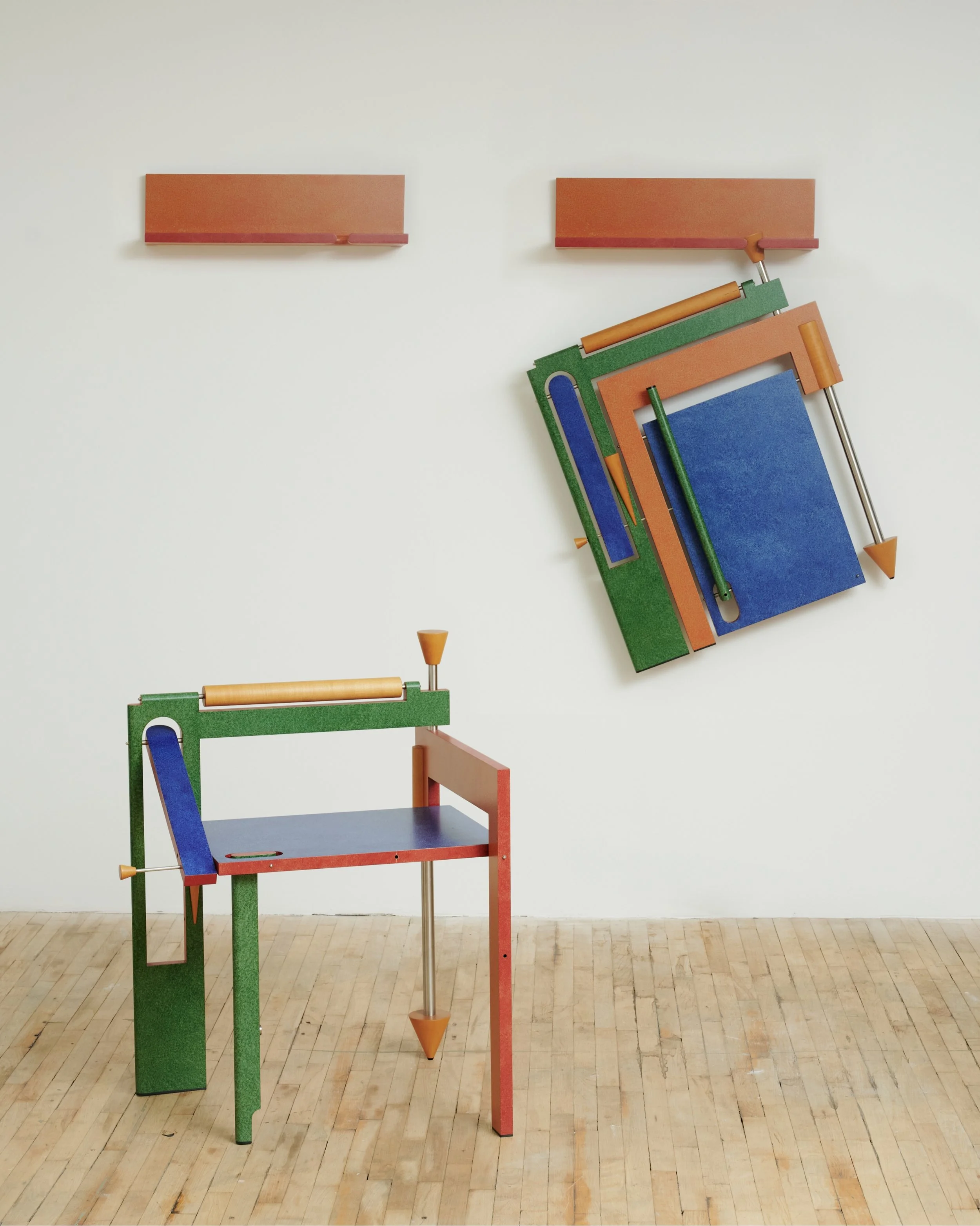 Colorful modern sculpture with geometric shapes and textured surfaces, including a cabinet-like structure, mounted on a white gallery wall with a wooden floor.