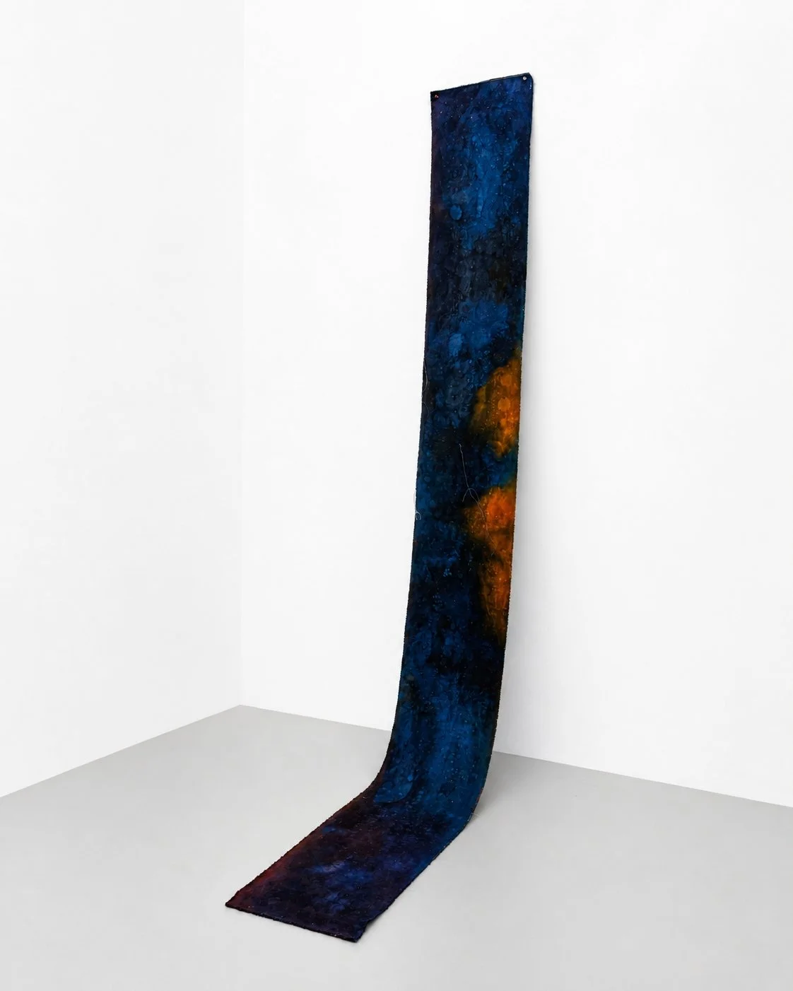 Long, narrow artwork with a galaxy-inspired design featuring dark blue and orange hues, hanging against a white wall. Vaughn Davis Jr.
