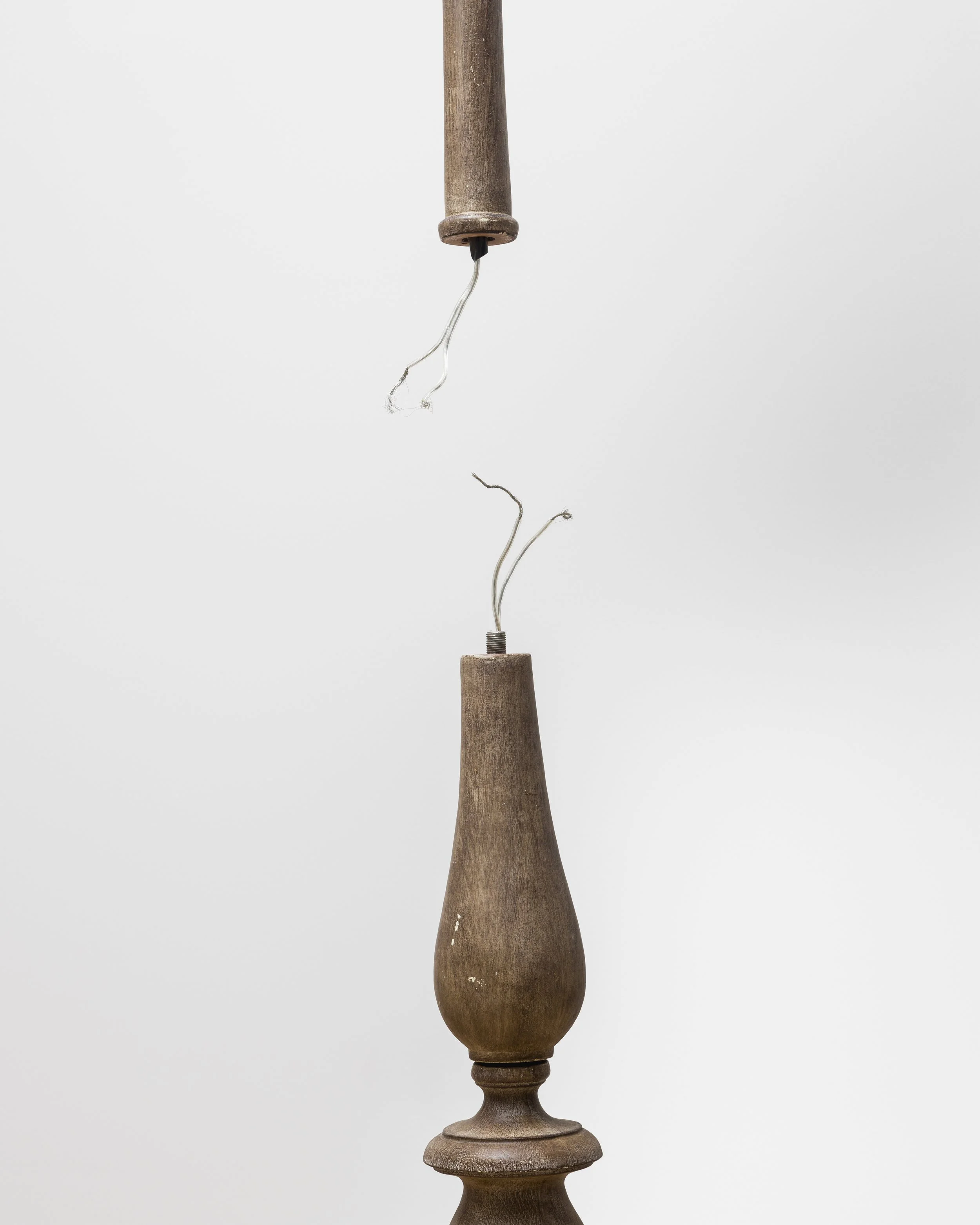 A wooden table lamp base with a brown finish, visible wood grain, and a turned design, set against a plain white background. Pippa Garner.