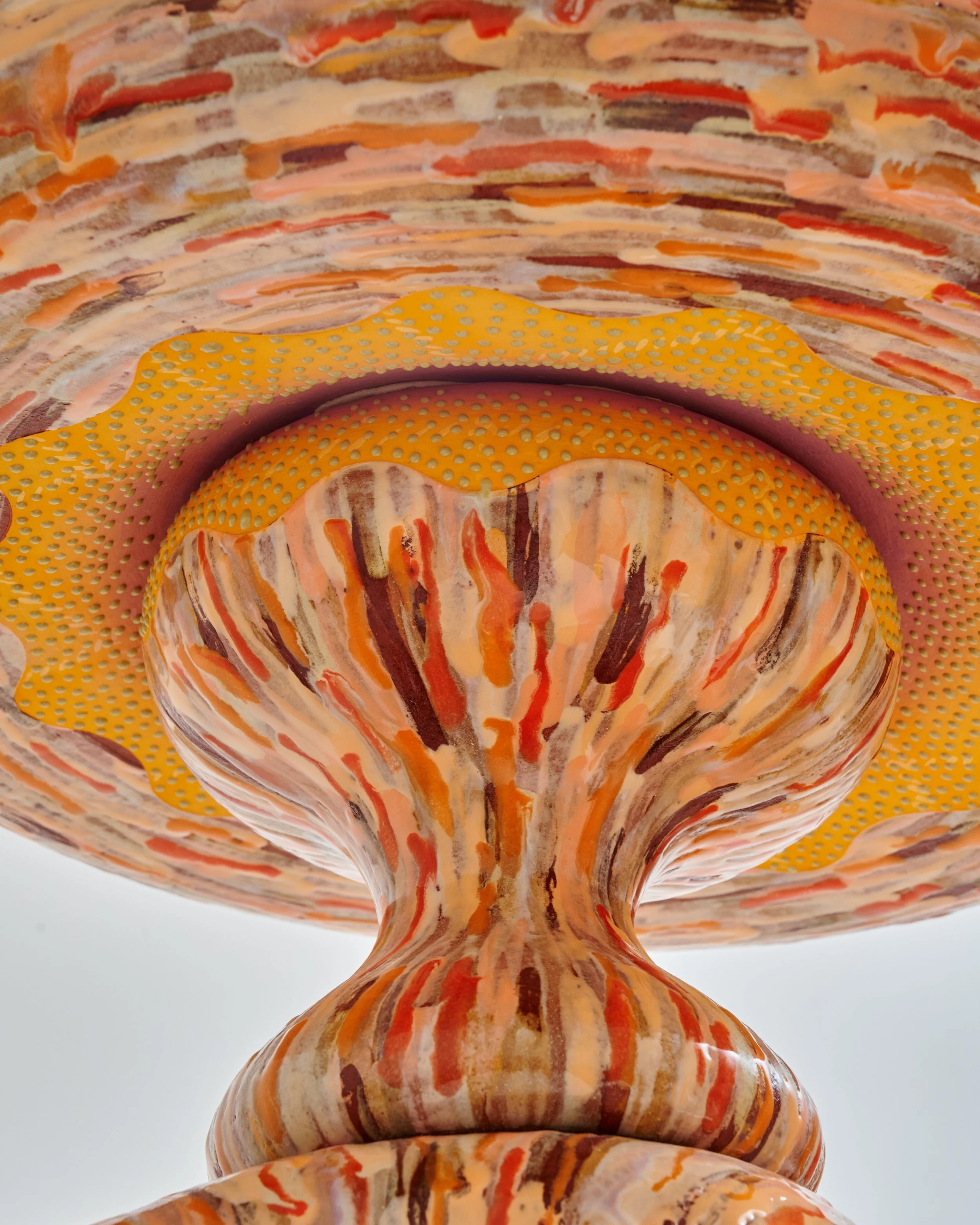 A colorful, abstract glass sculpture with swirling patterns in shades of orange, pink, beige, brown, and white, viewed from below. Joël Brodovsky-Adams.