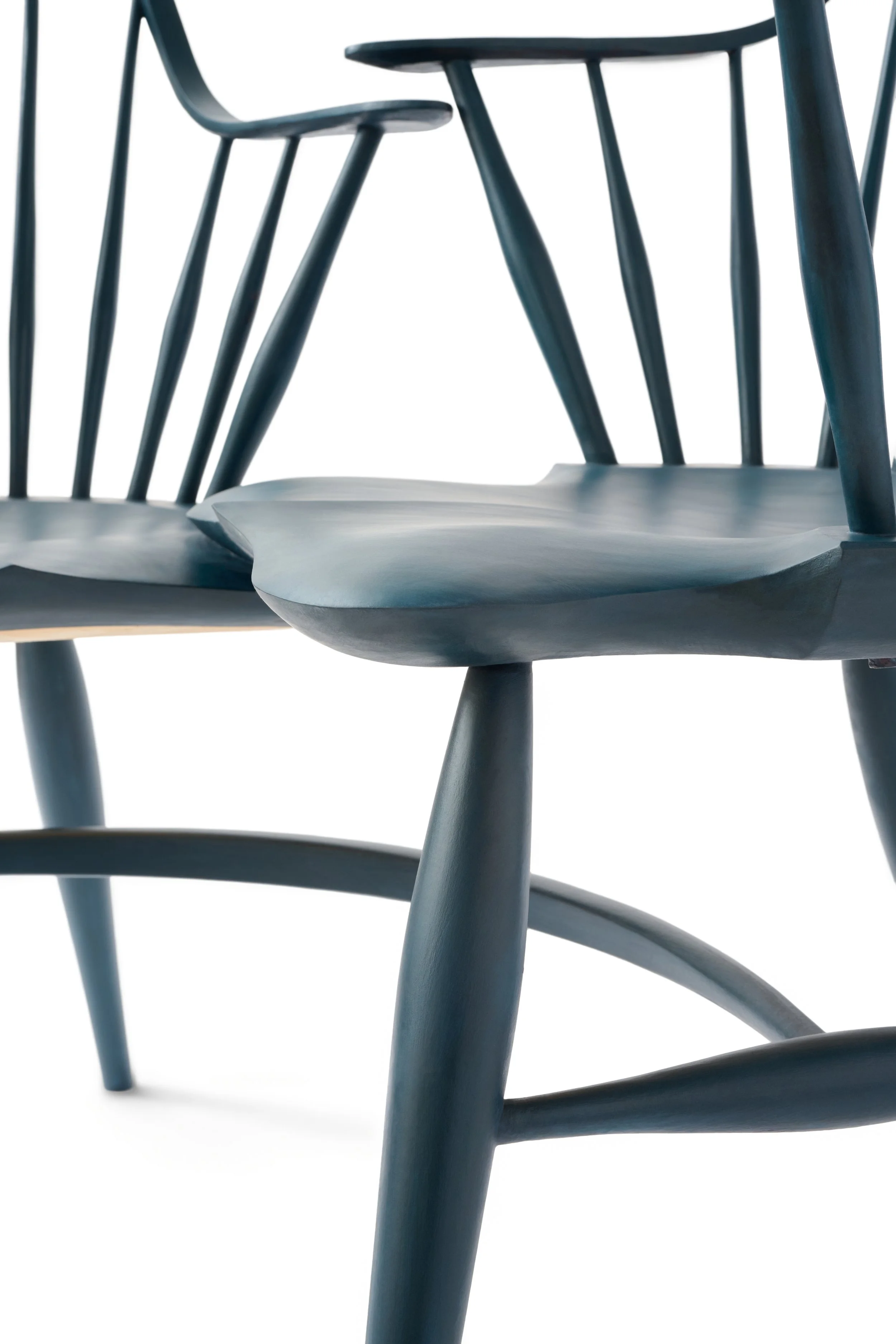 Close-up of a dark blue wooden chair with spindle back and curved seat, isolated on white background.