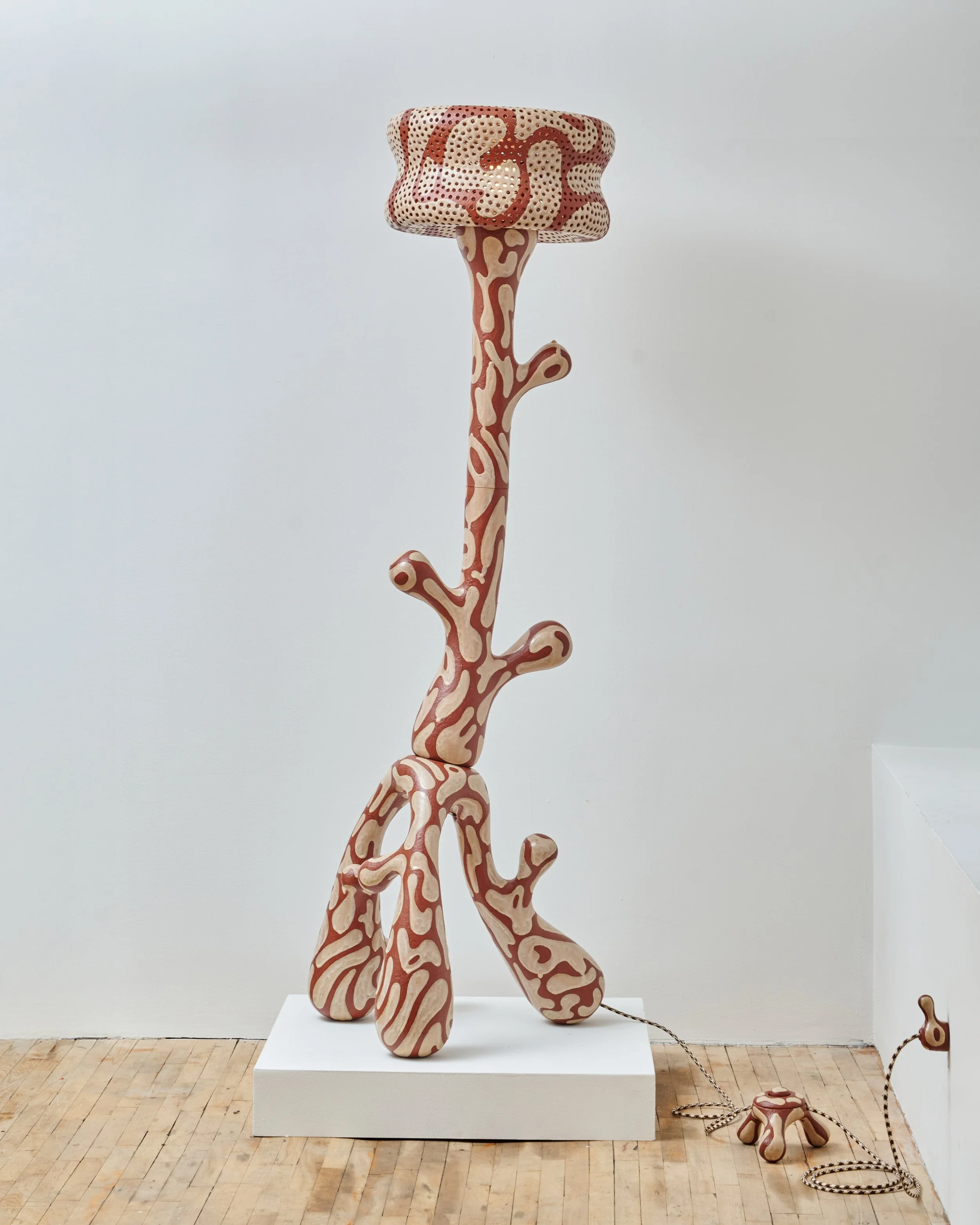 A large giraffe-shaped sculpture with a pattern of pink and cream colors, positioned in an art gallery. Joël Brodovsky-Adams.