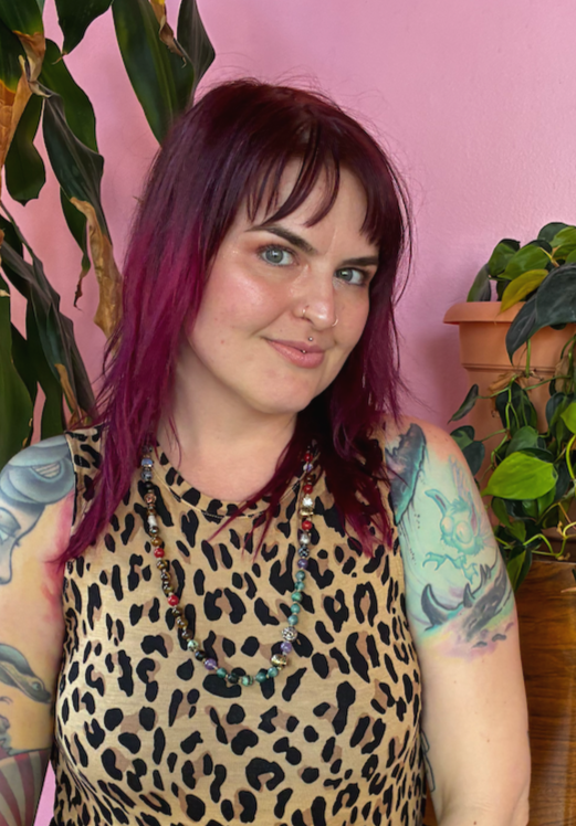 Women smiling standing next to a plant near a pink wall