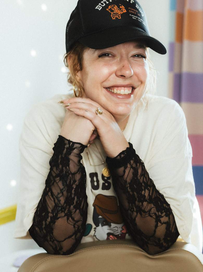 Smiling woman with a black hat leaning on a salon chair
