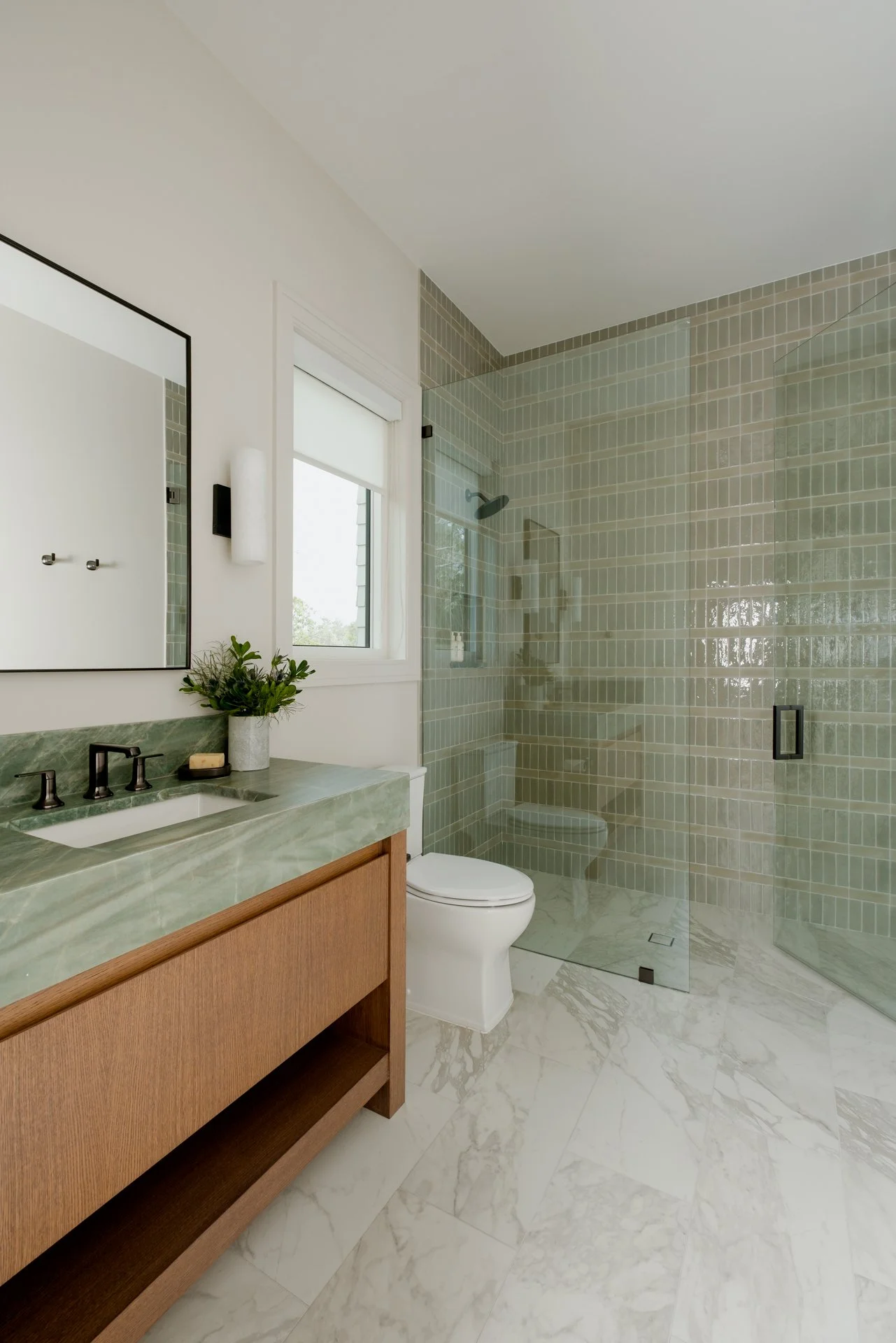 A fun guest bathroom with fun pattern play in a green shower wall tile that ties in the green vanity countertop.