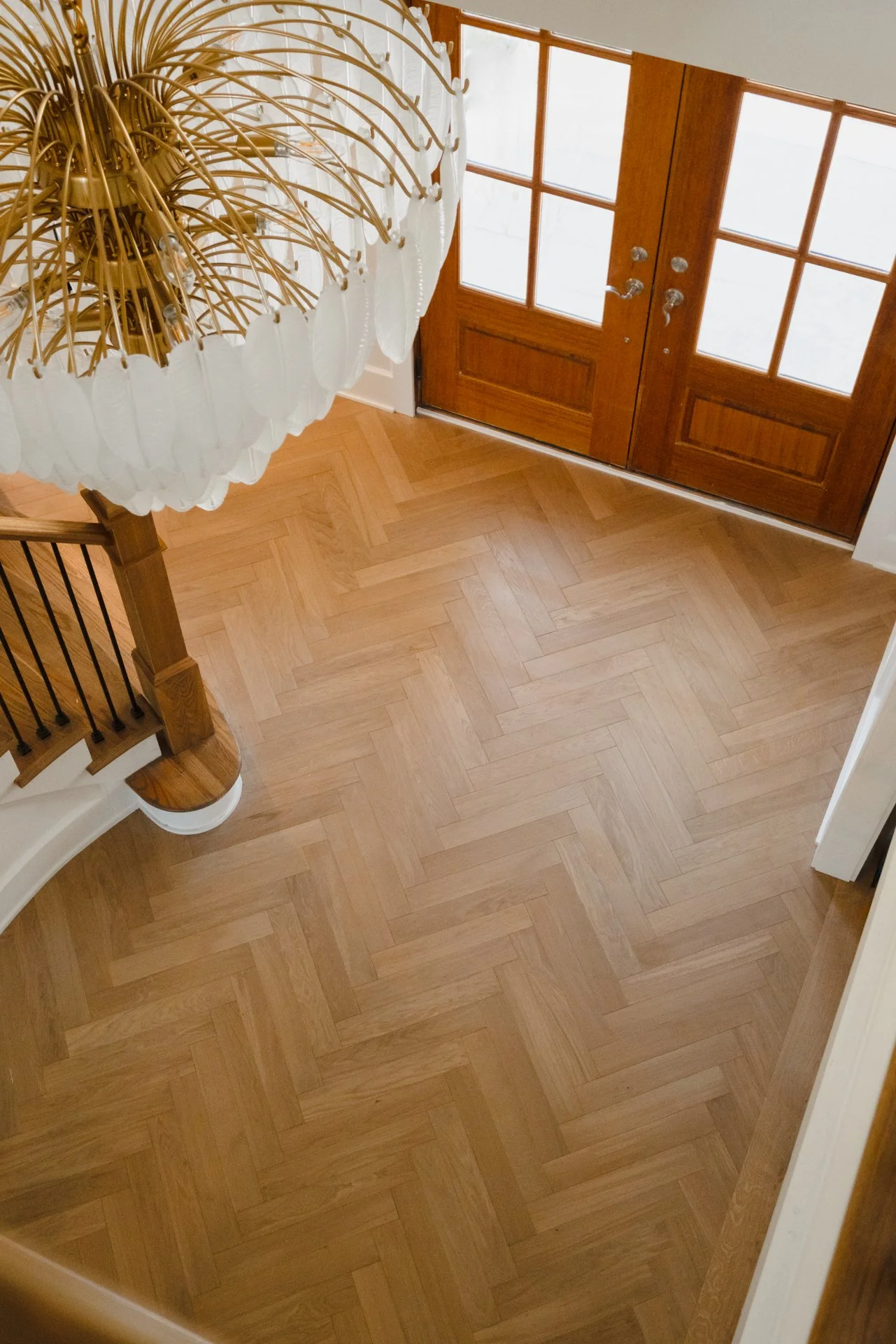An overview shot of a home entryway featuring custom Riva hardwood floors in a herringbone pattern, making a statement for the first steps inside.
