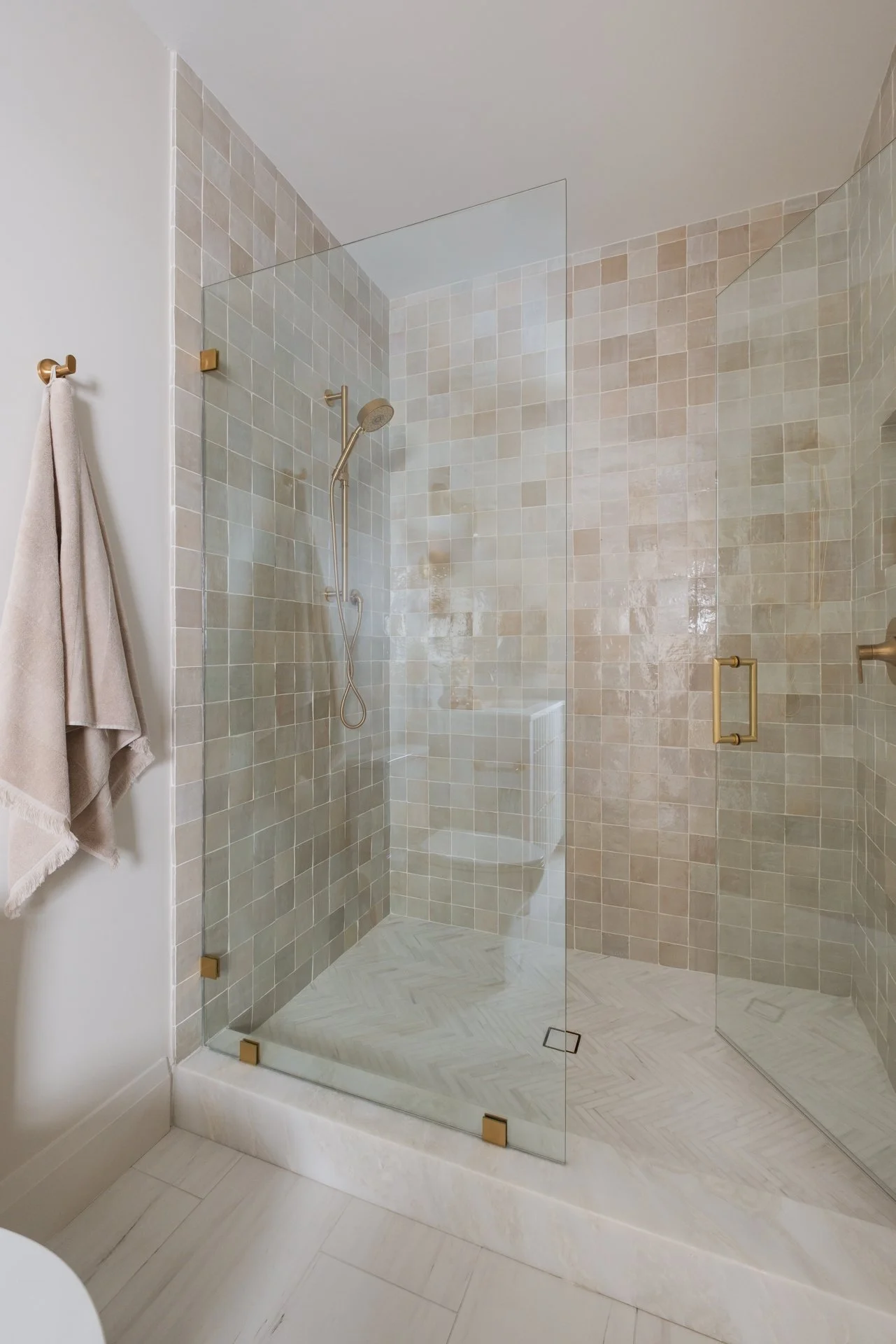 A guest bathroom with soft neutral colors in 4x4 square tiles with bronze accents.