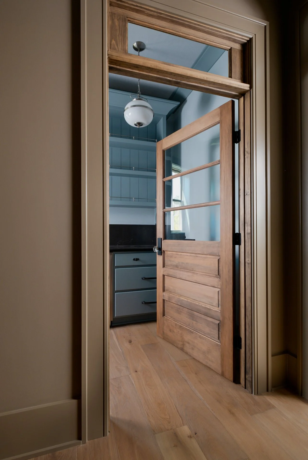 A warm butler's pantry showcasing Fabrica hardwood floors throughout the home tying in the warm tones and textures. Color-drenched walls and fun blue cabinets.