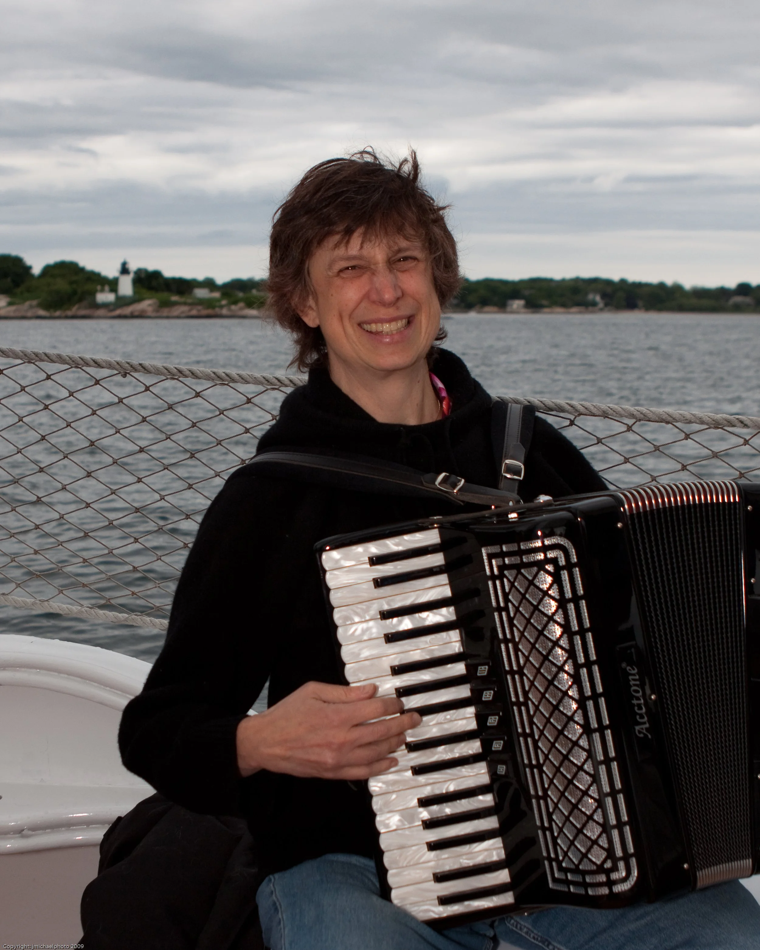 Susie Petrov with accordion - water in background