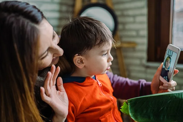 A woman and a boy having a video call on a smartphone indoors.