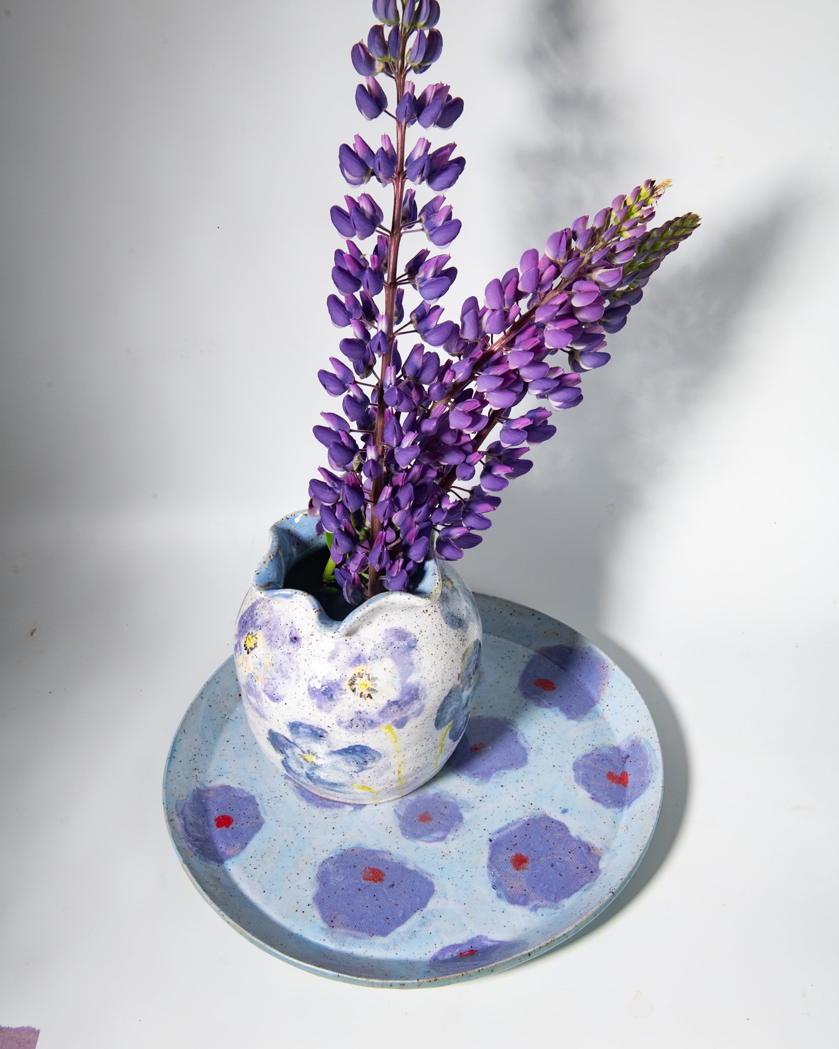 Handmade purple poppy vase with lupines sitting purple poppy plateon a