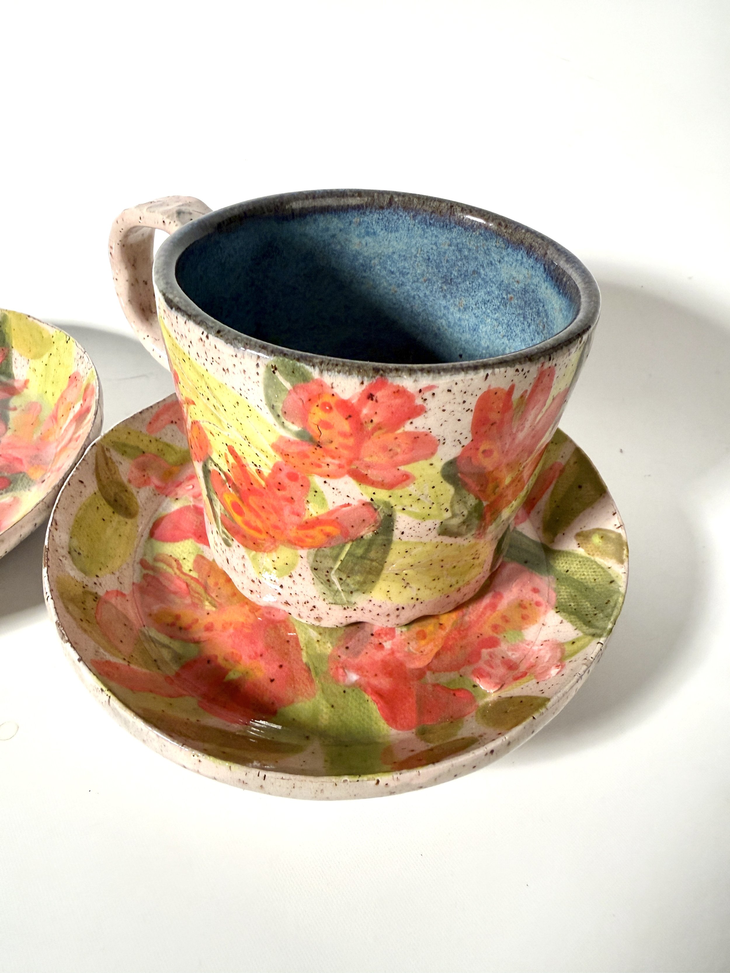 Handmade Ceramic mug with pink tropical orchids sitting on a tropical orchid saucer