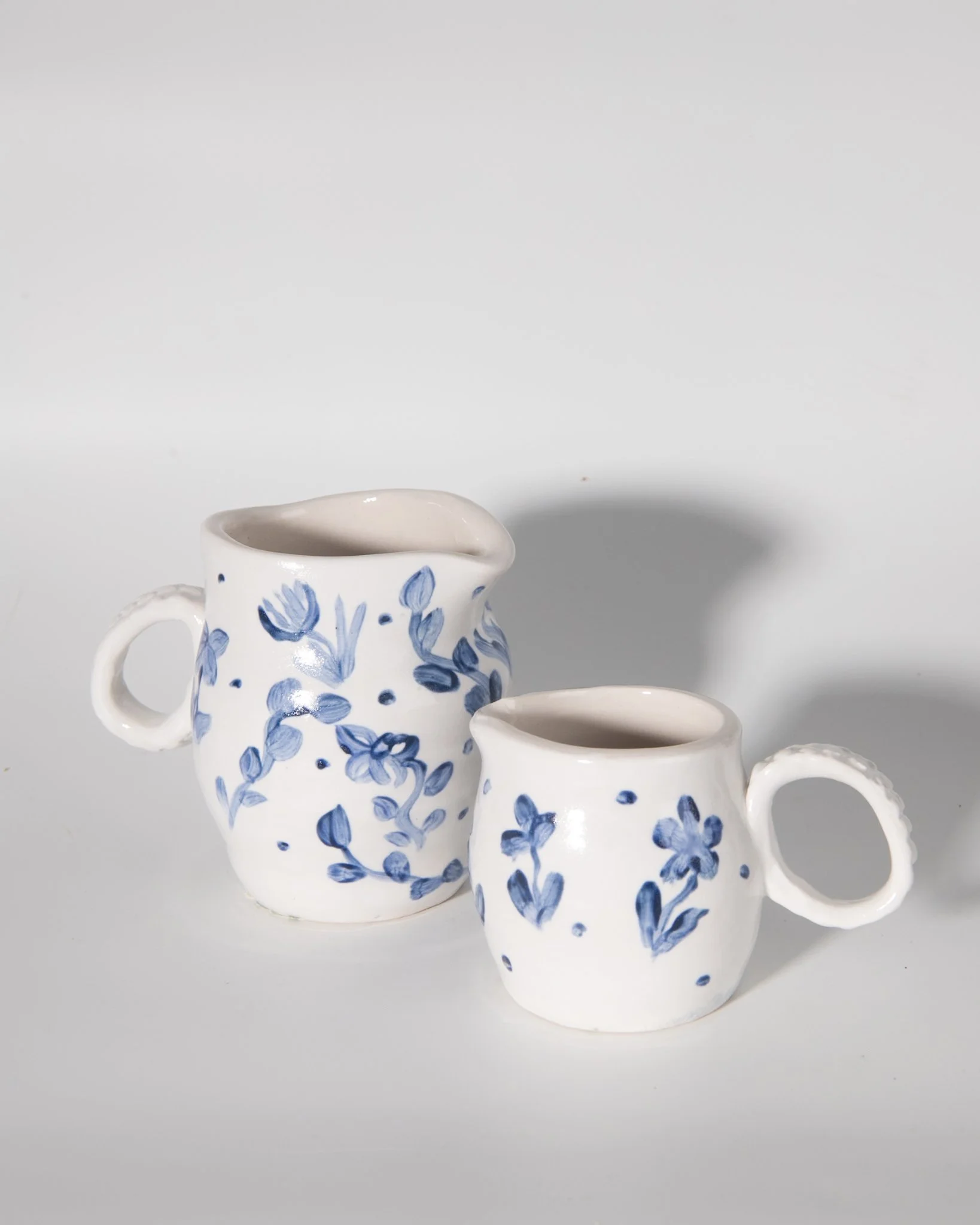 Two Small Handmade Porcelain Pitchers decorated with Simple Blue Flowers