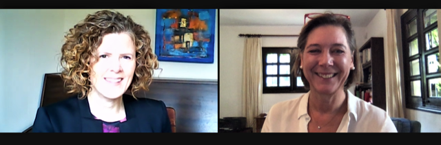 Two women smiling in a video call, each in their own room with windows and art or decor in the background.