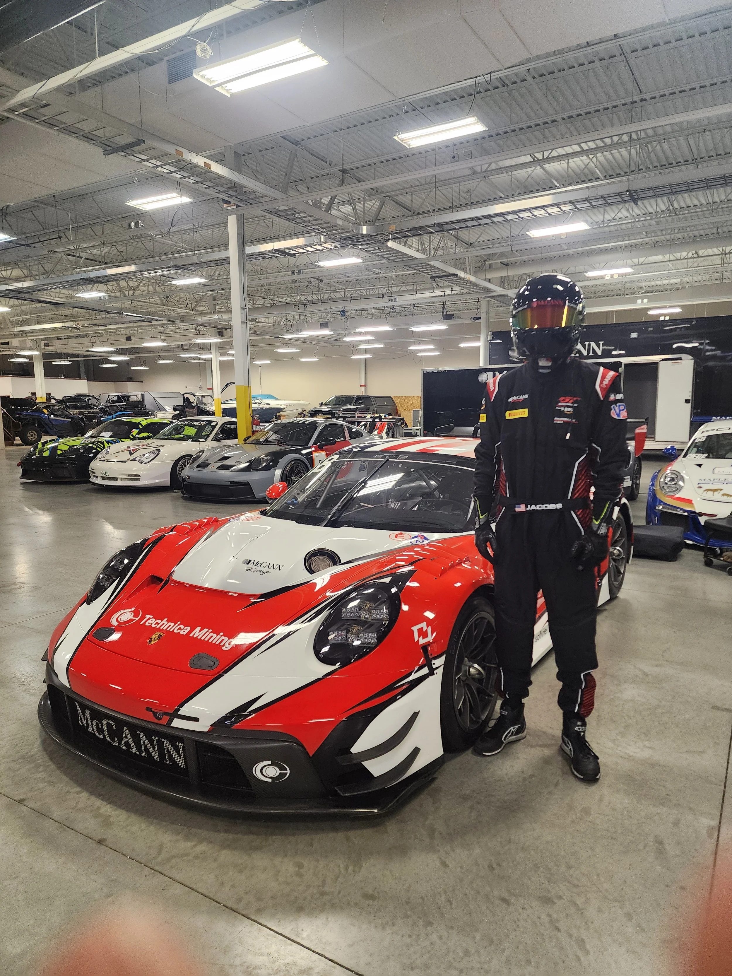 Marina Racewear Pitt crew custom suit . James poses in front of McCann Racing GT3 R EVO Porsche