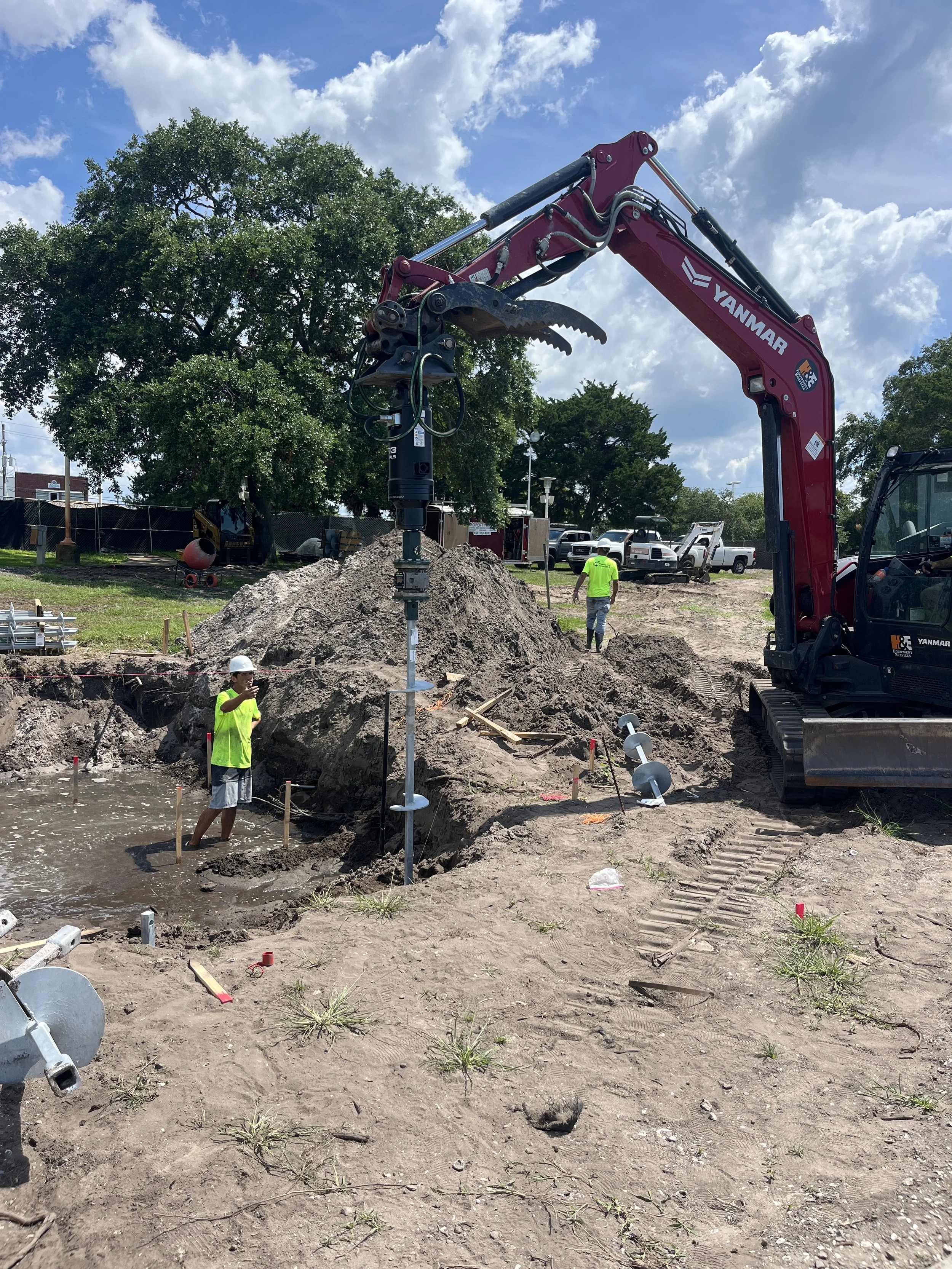 Helical anchor installation Florida Panhandle showing multiple CHANCE anchors installed and Yanmar excavator on site