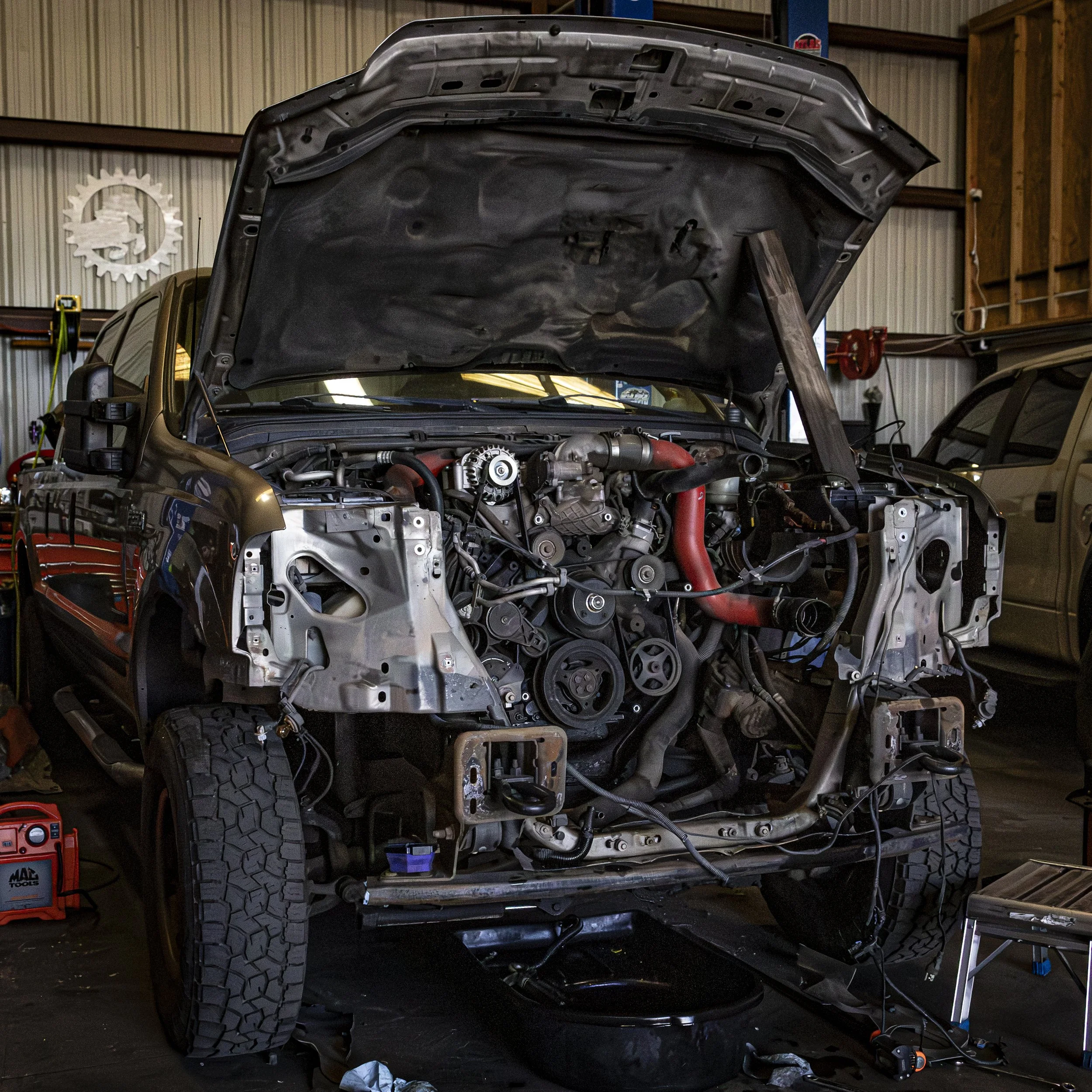 View of a car with its hood open inside a garage or workshop.