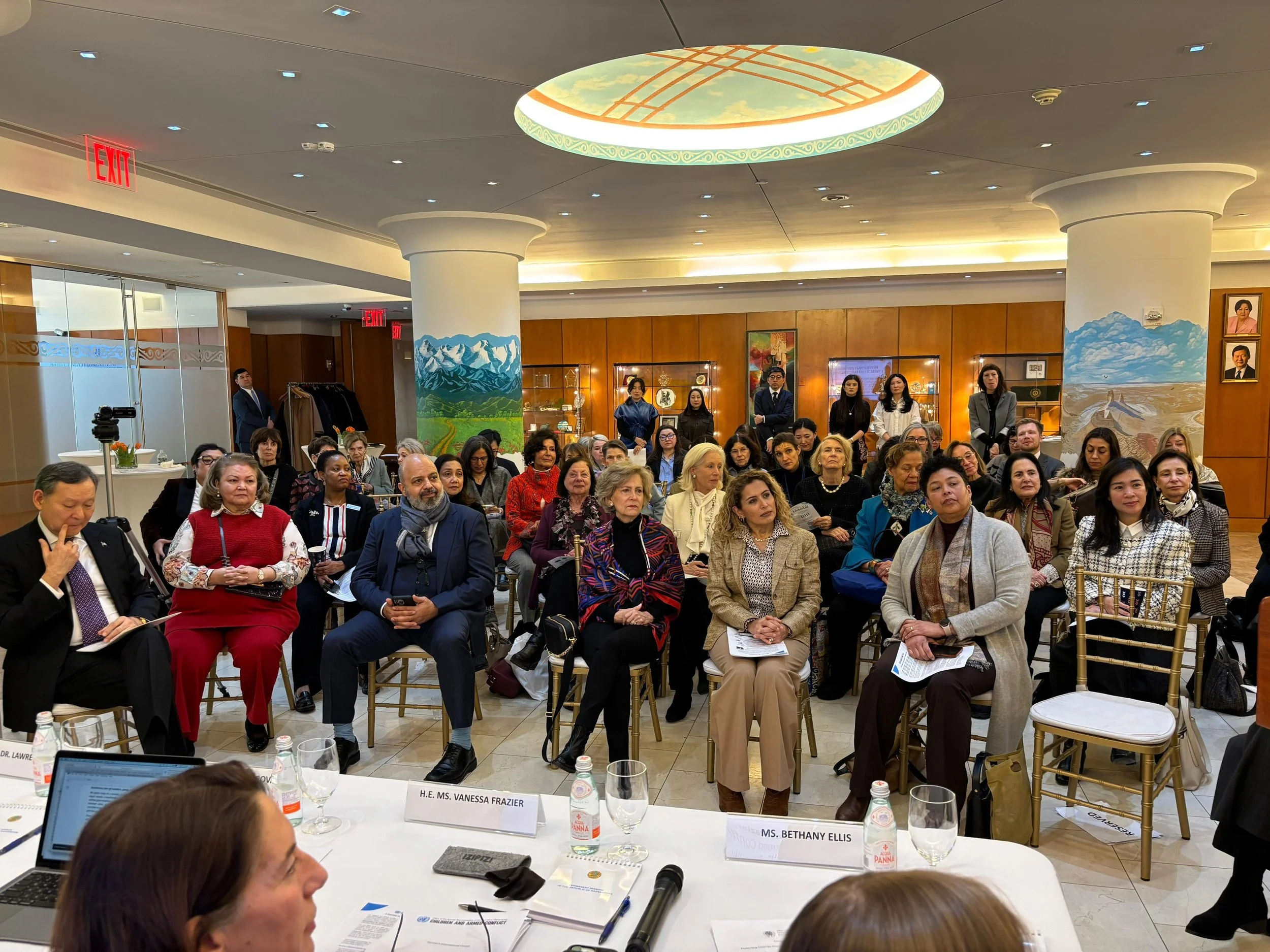 Audience sitting in a large room listening to a person who is speaking but not pictured.