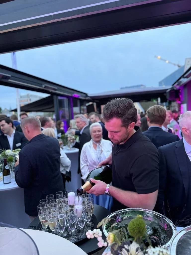 En servitør som skjenker champagne til gjester under en mottakelse på takterrassen hos Tom And Lello.jpeg