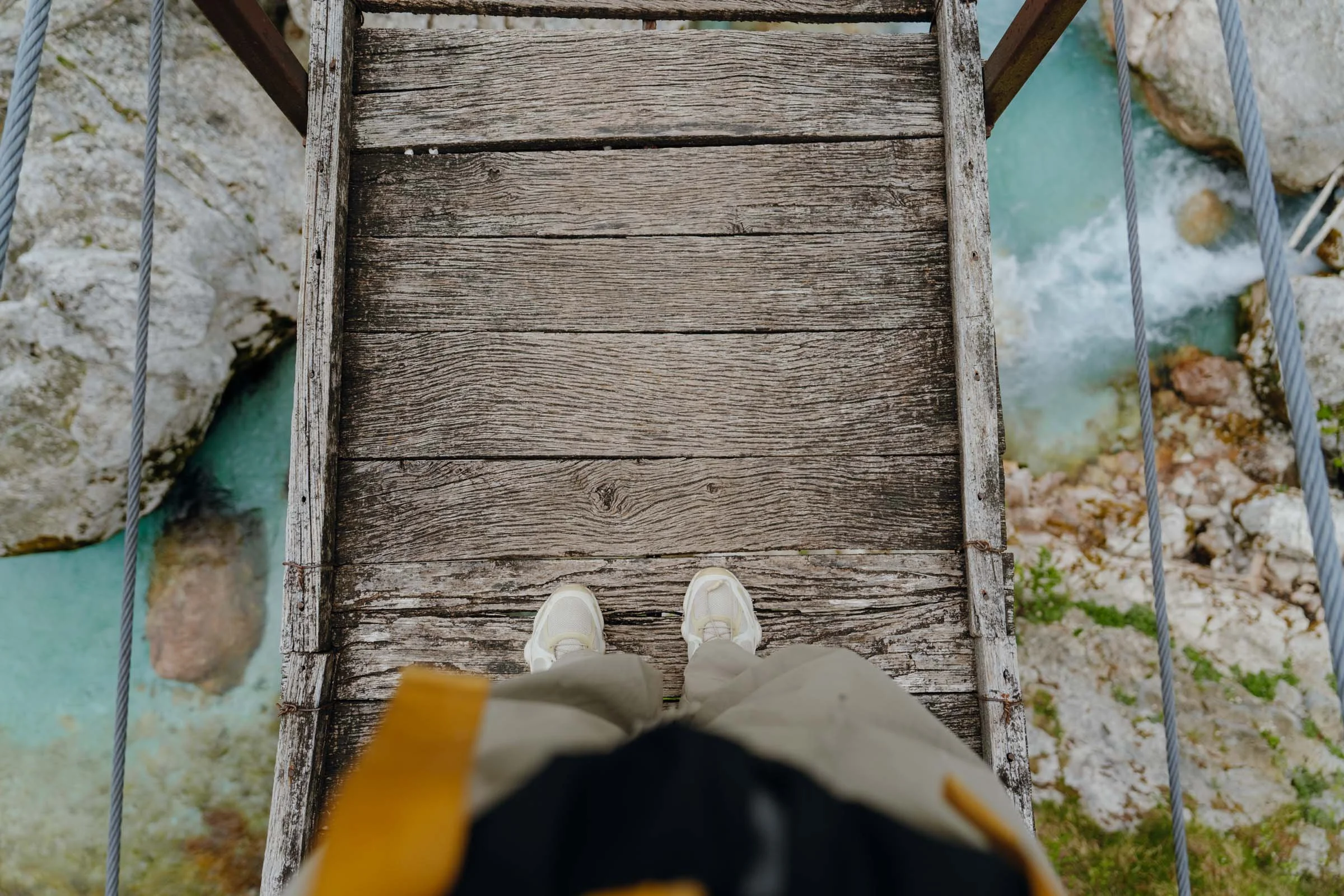 Woman standing on suspension bridge in hiking clothes in the Soca Valley, Alpe Adria Trail, Slovenia