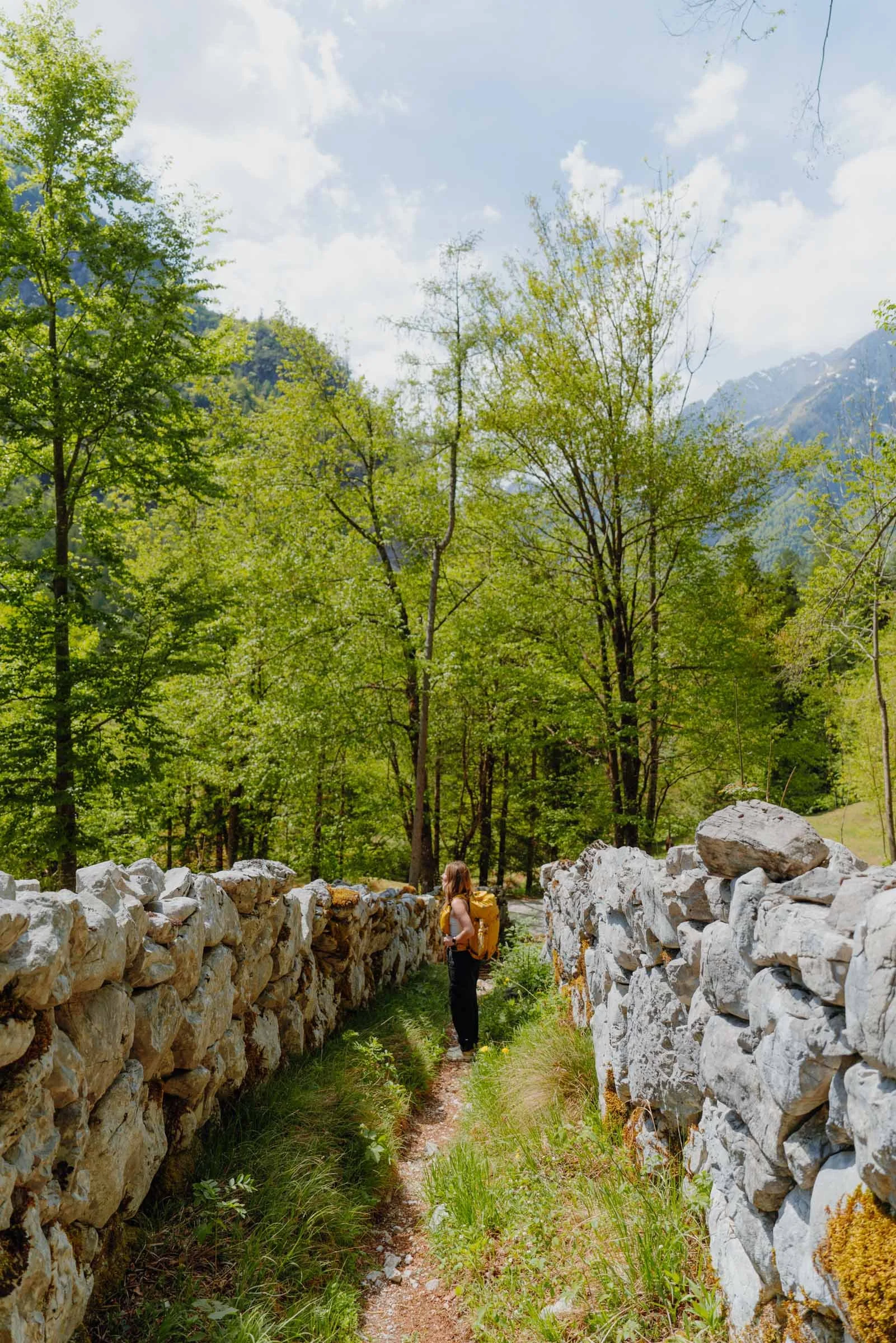 Woman standing between stone walls in the Soča Valley of Alpe Adria Trail, Slovenia