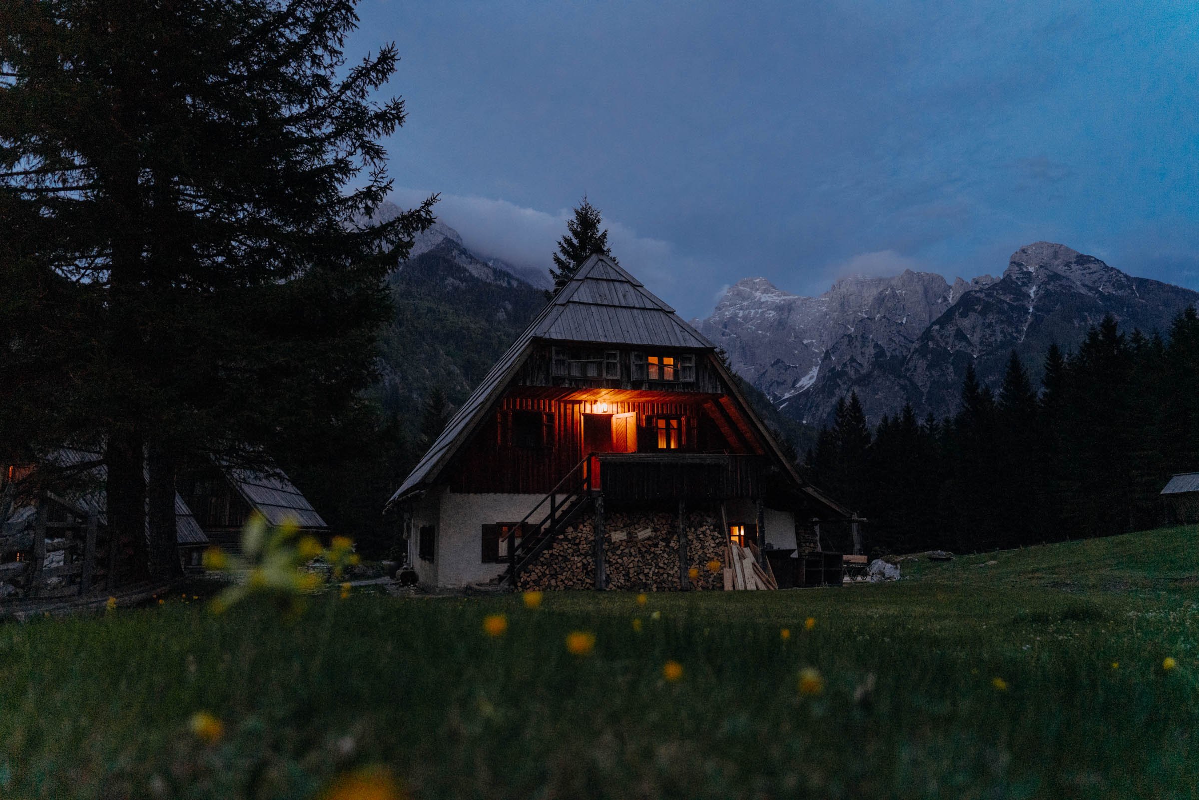 Secret waterfall, Kekčeva Domačija mountain hut after dark with flowers in the foreground, Alpe Adria Trail, Slovenia