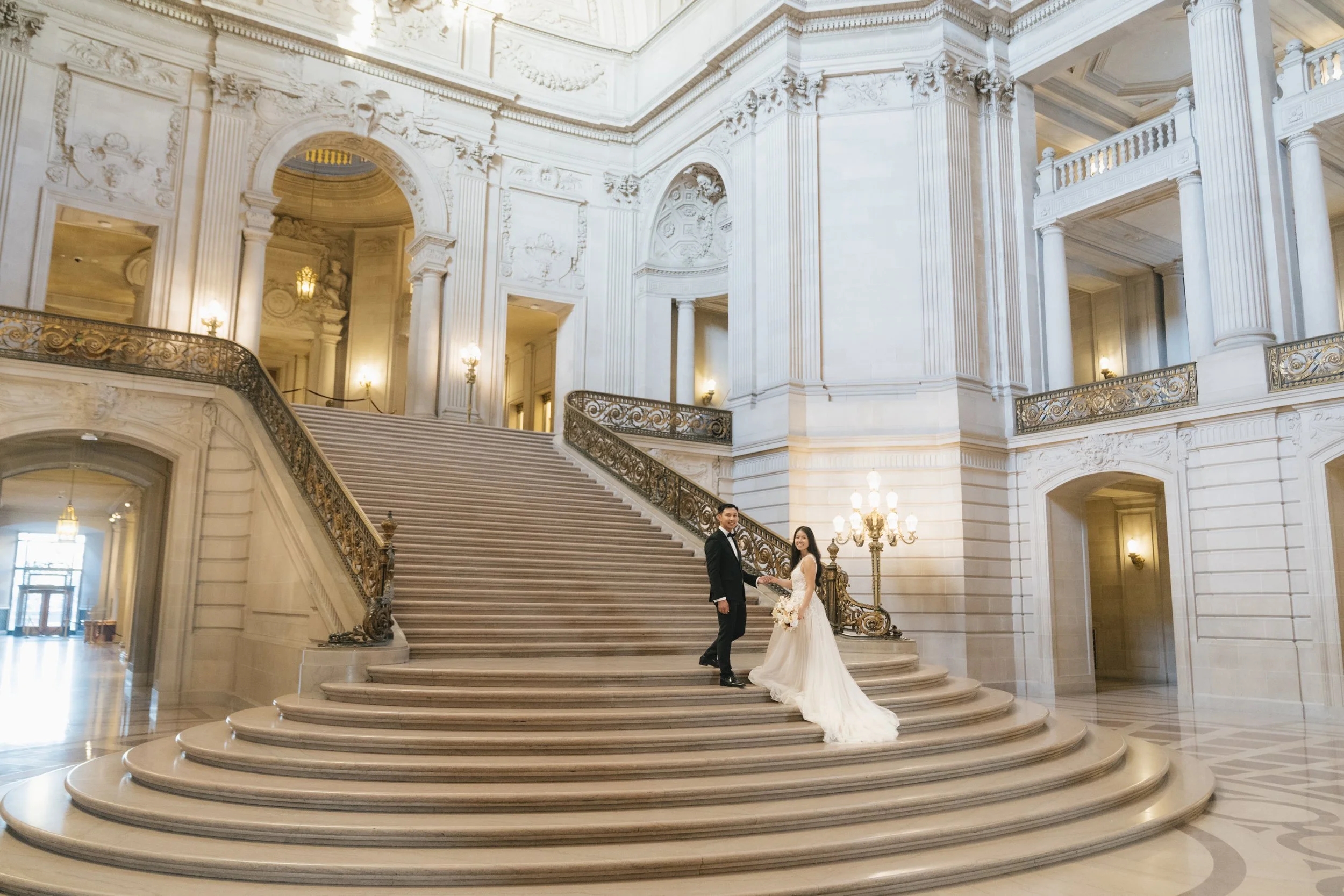 couple taking photos on grand staircase at San Francisco city hall