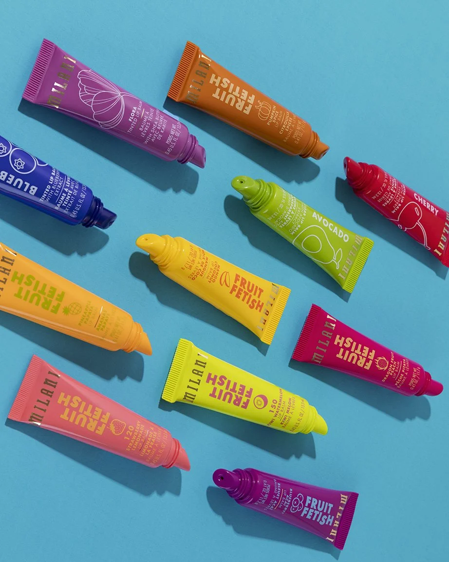 Assorted colorful fruit-flavored lip balms arranged on a bright blue background.
