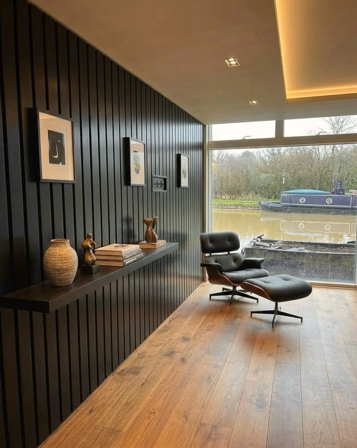 Dark wood, soft lighting, and a view of the water. Paneling this main wall instantly anchored the space and brought in that moody, mid-century atmosphere. Easily one of my favorite details in this build so far. 🌿🛋️#MidCenturyModern #LuxuryInteriors