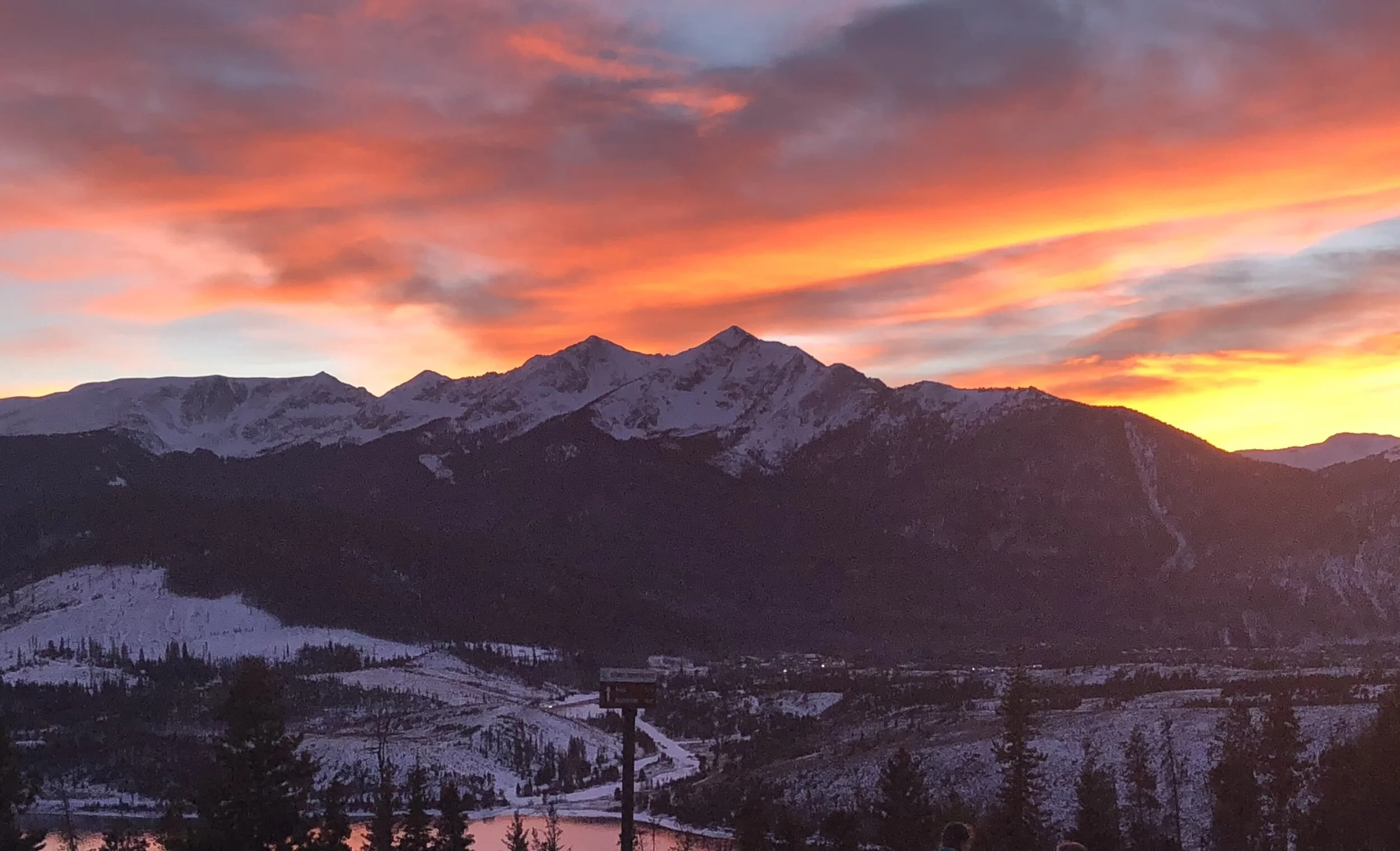 Colorful sunset over snowy Vail Valley mountains and evergreen trees