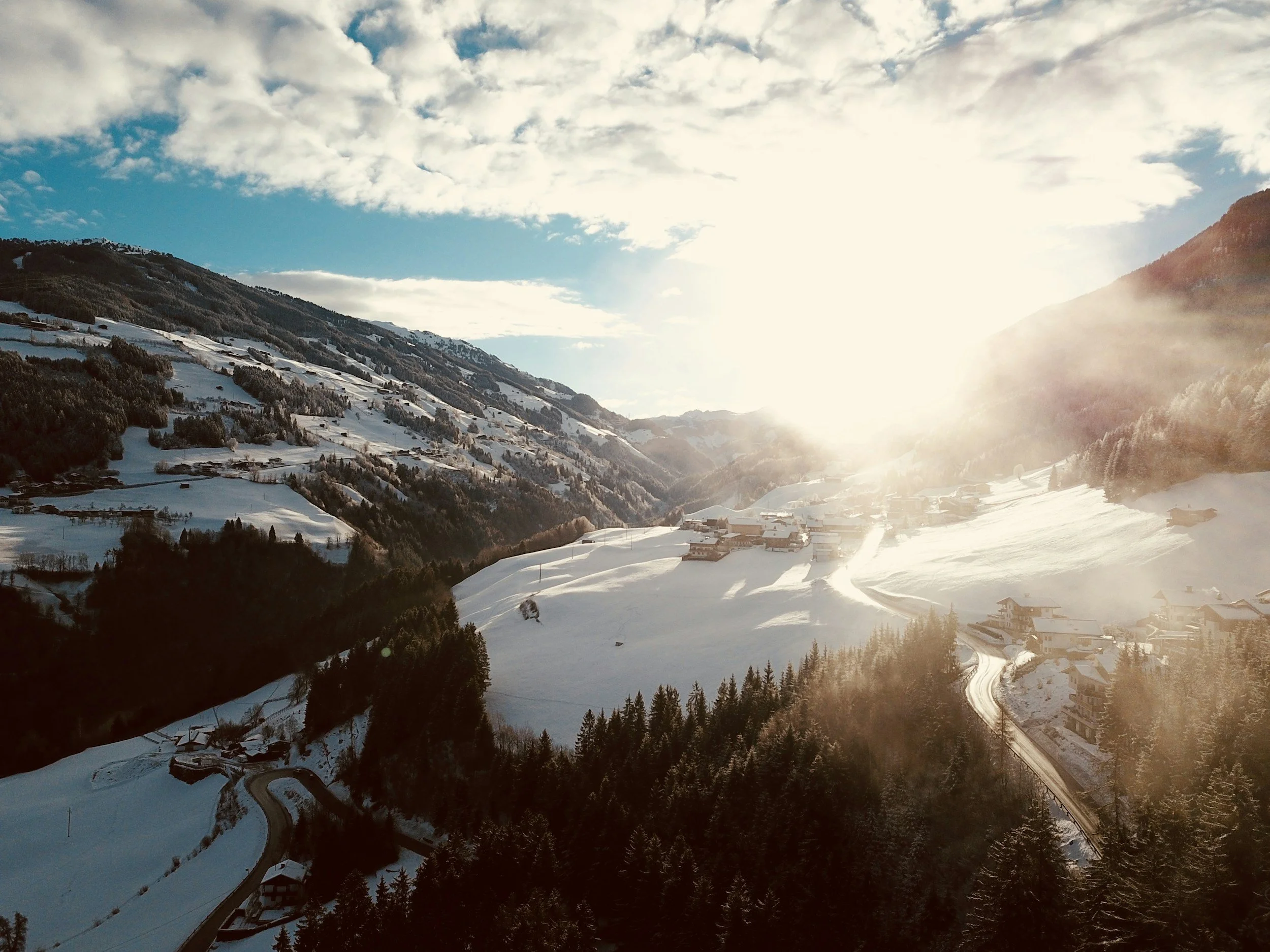 Sunlight over a snowy mountain valley and evergreen forest