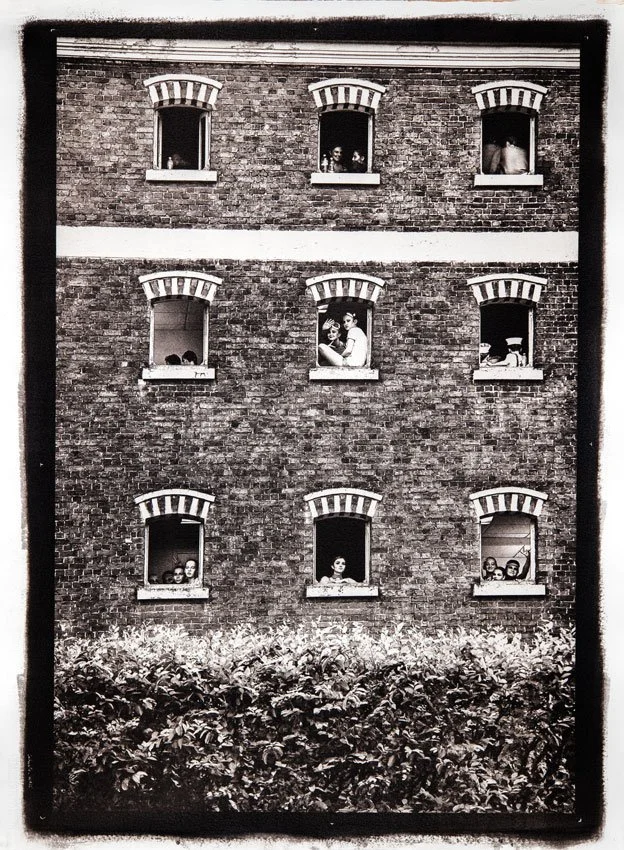 Façade en briques avec fenêtres ouvertes et artistes interagissants, composition graphique en noir et blanc