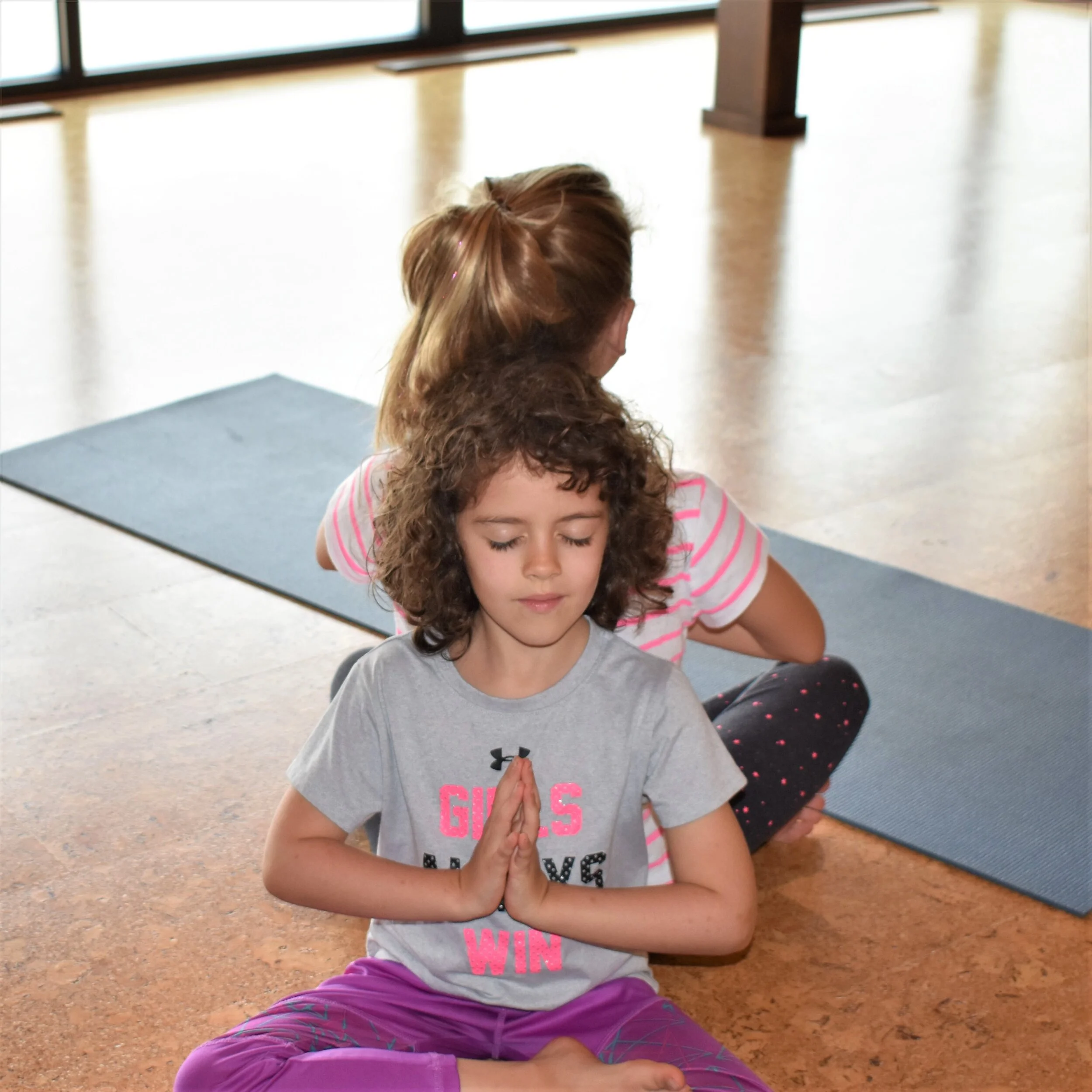 alt= "child in easy pose with prayer hands being mindful"