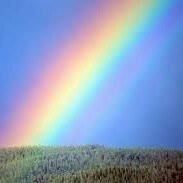 alt= "rainbow over mountains and blue sky"