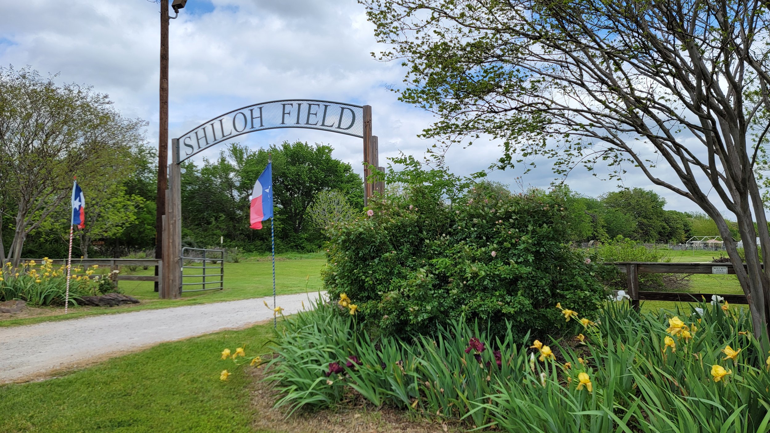 Metal sign posted high above a road that says Shiloh Field.