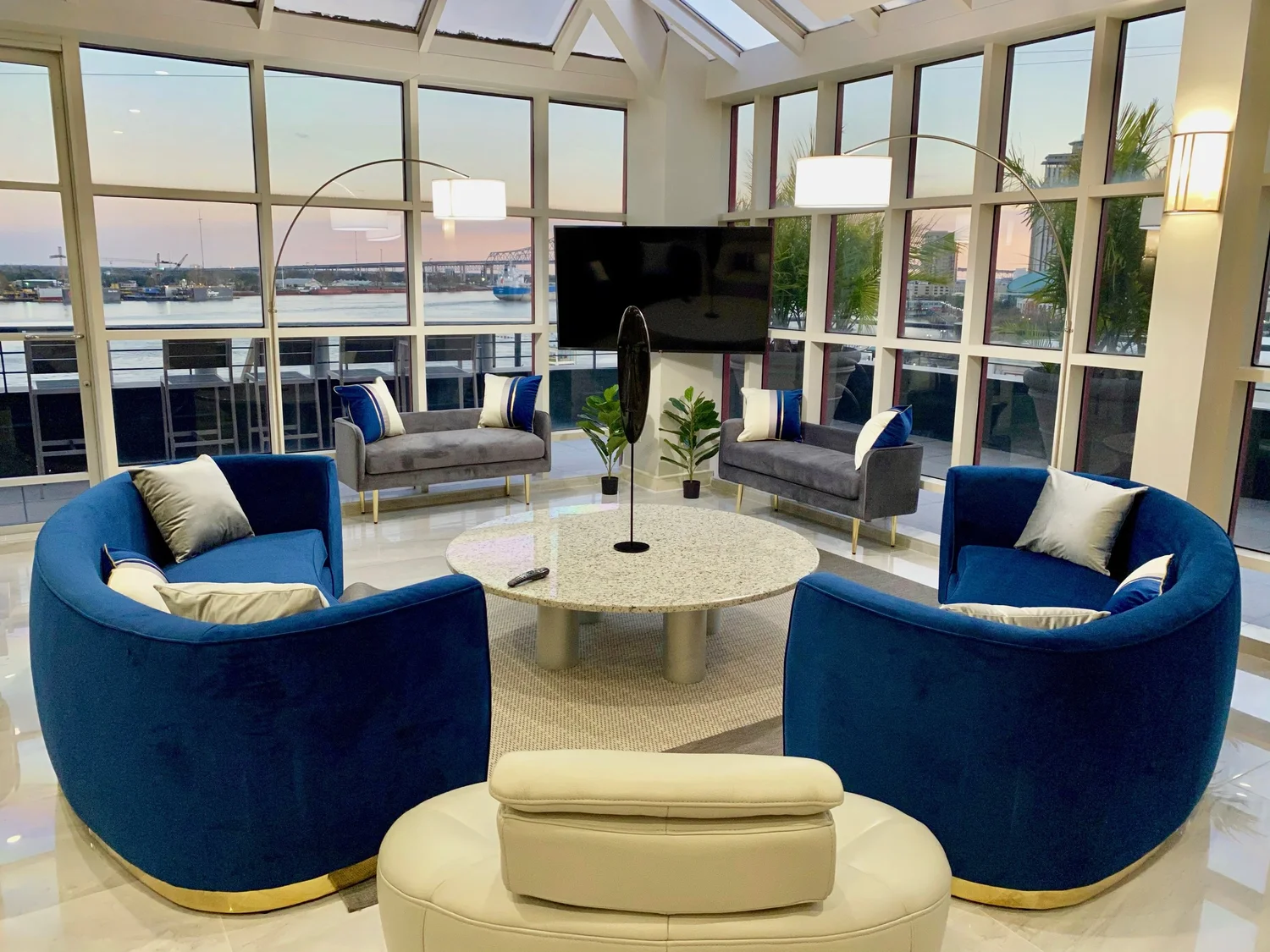 Glass-walled living room with blue armchairs and river views in The Penthouse at Jax Brewery