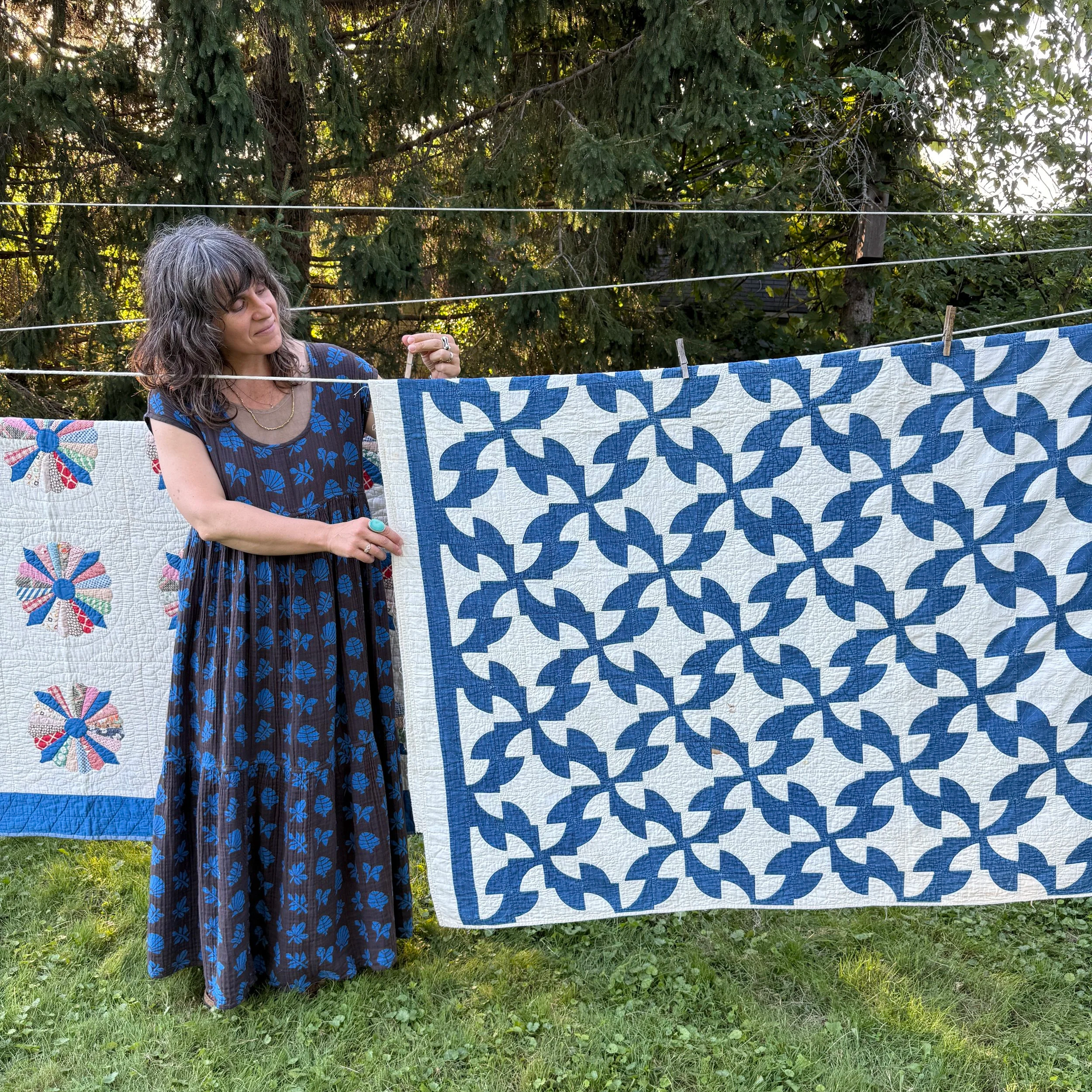 Katrina Rodabaugh stands at the clothesline with vintage quilts.