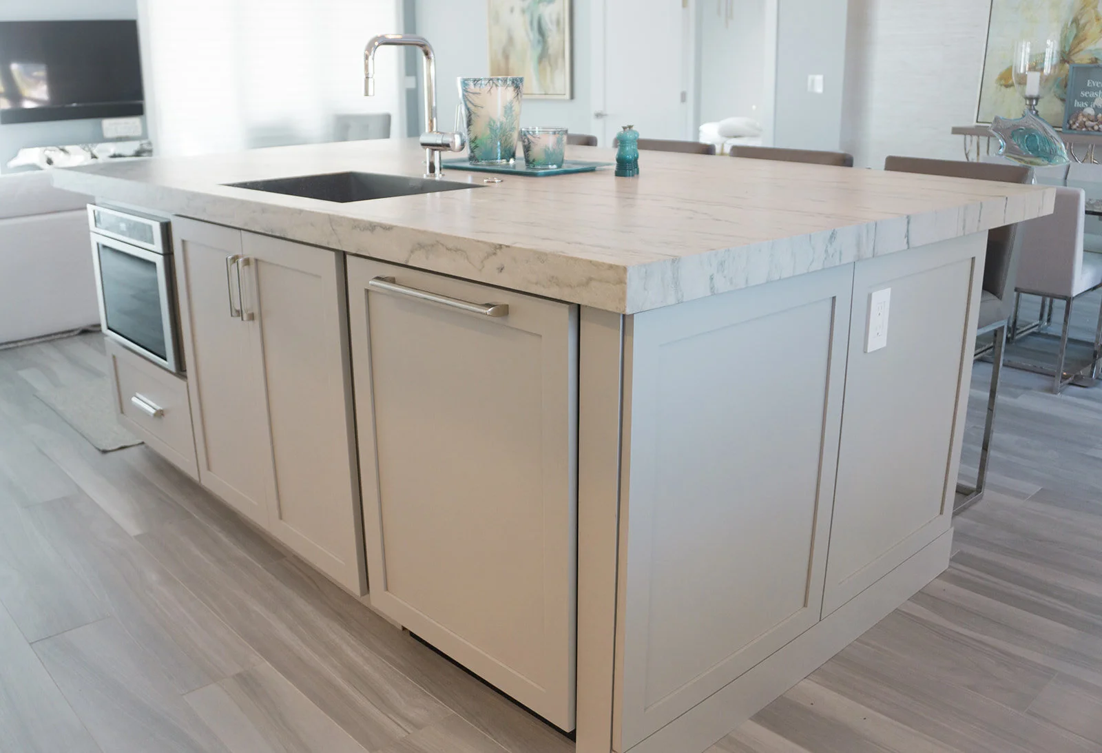 Modern kitchen island with a marble countertop, sink, and cabinetry, set in a bright, contemporary home.