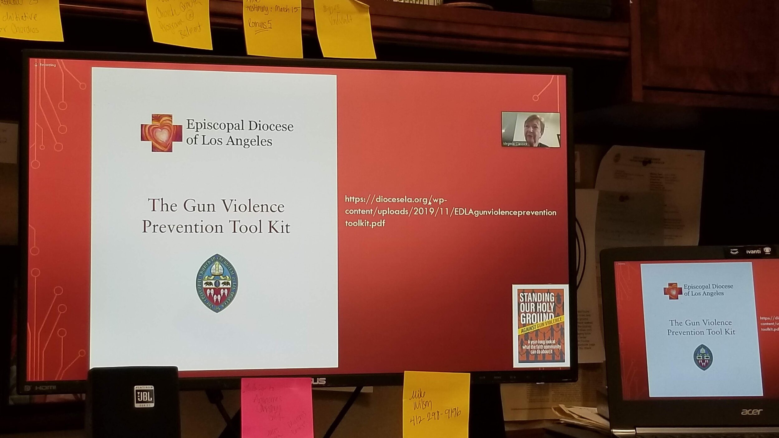 A computer monitor displays a presentation titled 'The Gun Violence Prevention Tool Kit' by the Episcopal Diocese of Los Angeles. There are post-it notes on the screen. A smaller screen showing a similar slide is partially visible.