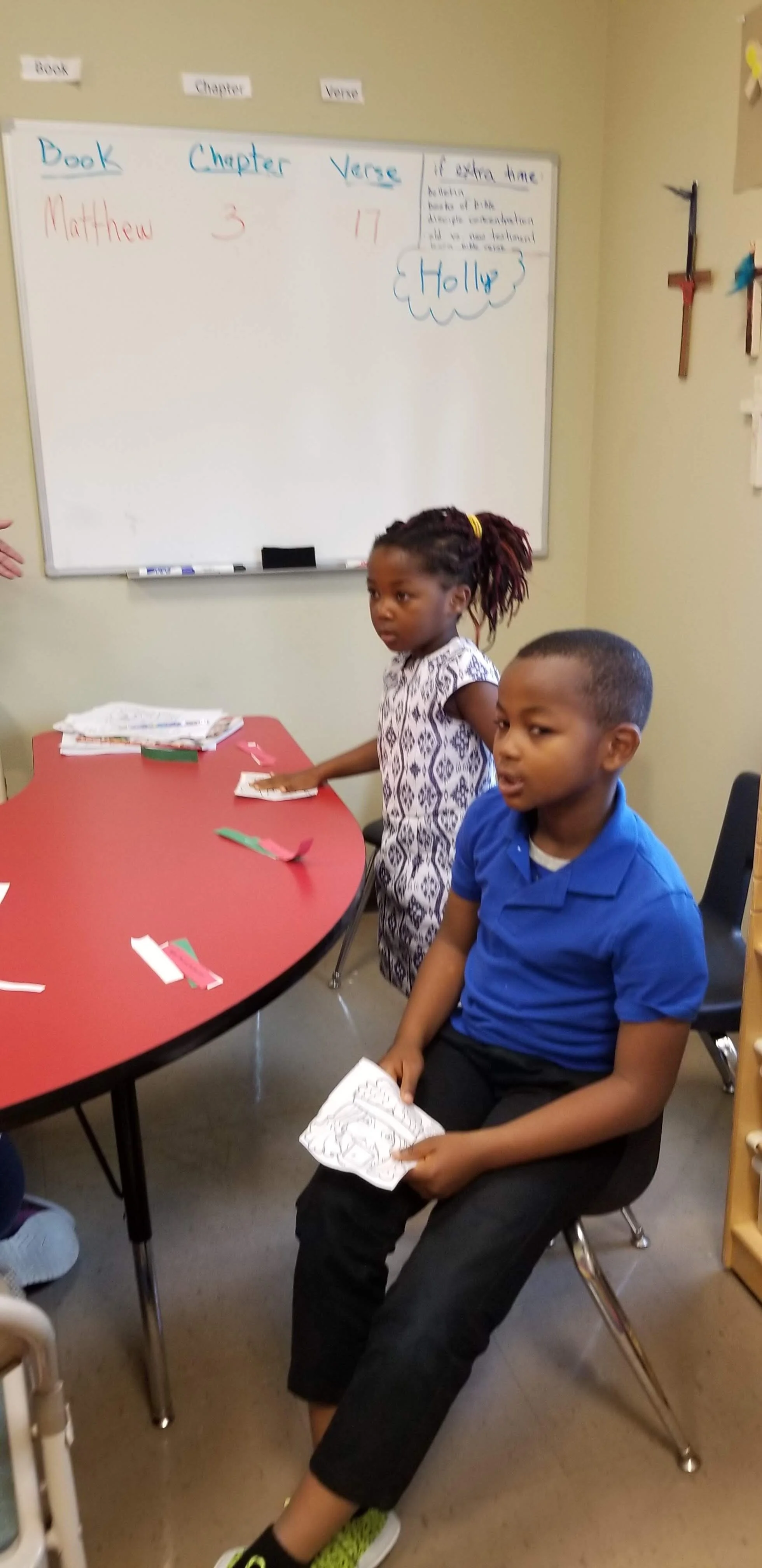 Children in a classroom with Bible verse on whiteboard