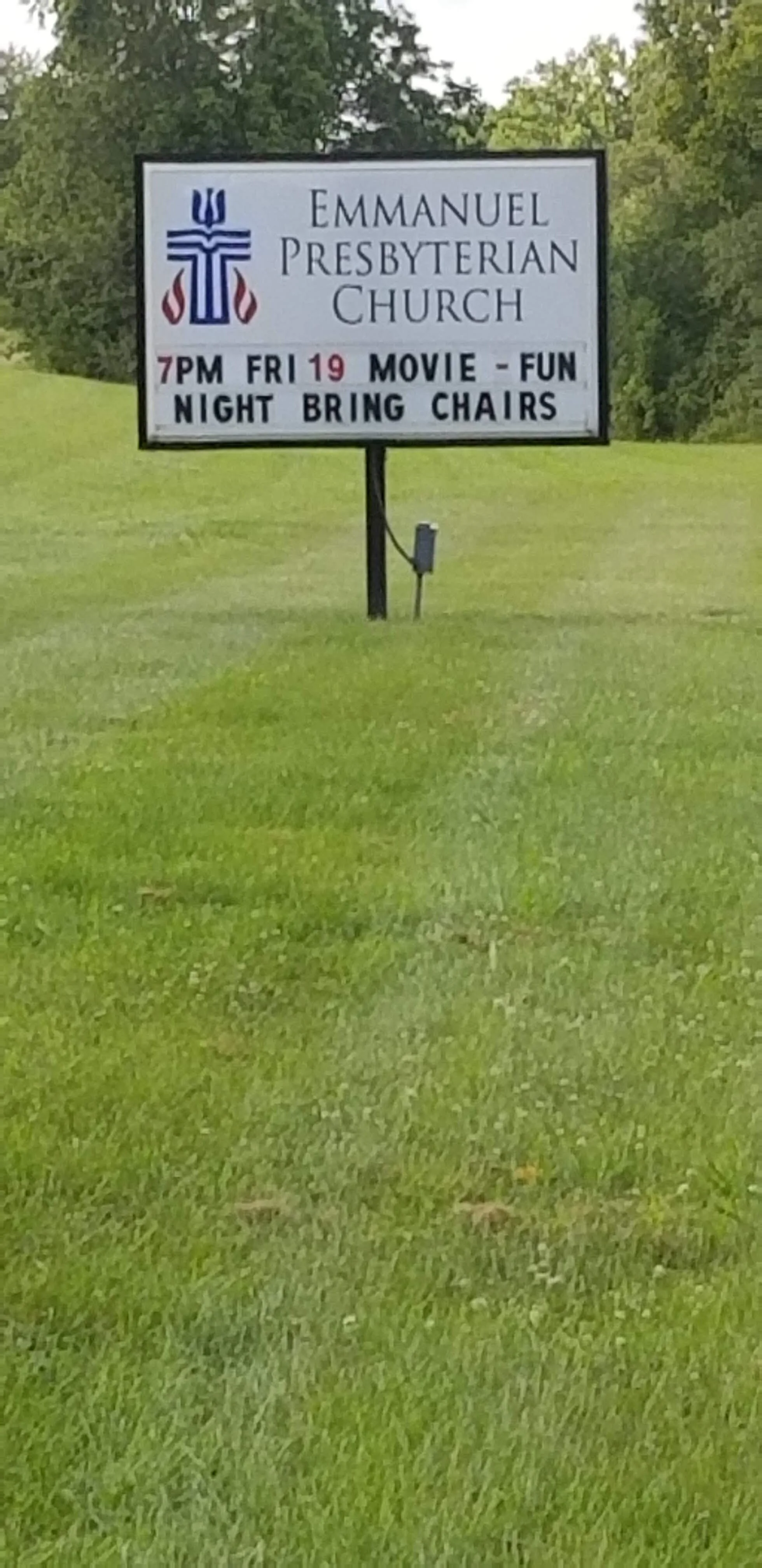 Sign for Emmanuel Presbyterian Church with information about a movie night event on Friday, 19th at 7 PM, advising to bring chairs.