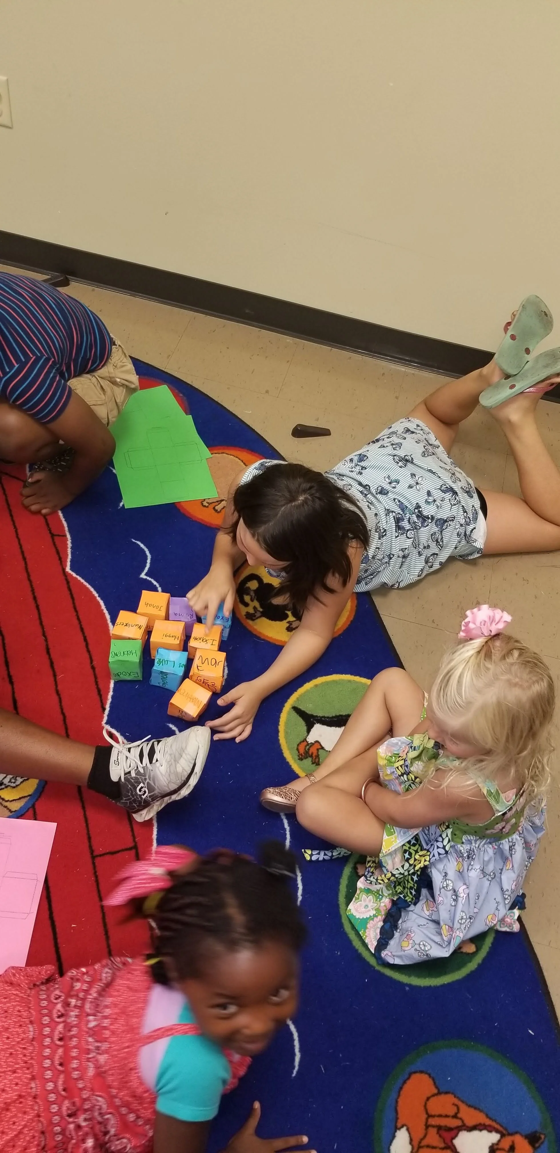 Children playing with blocks on a colorful rug indoors.