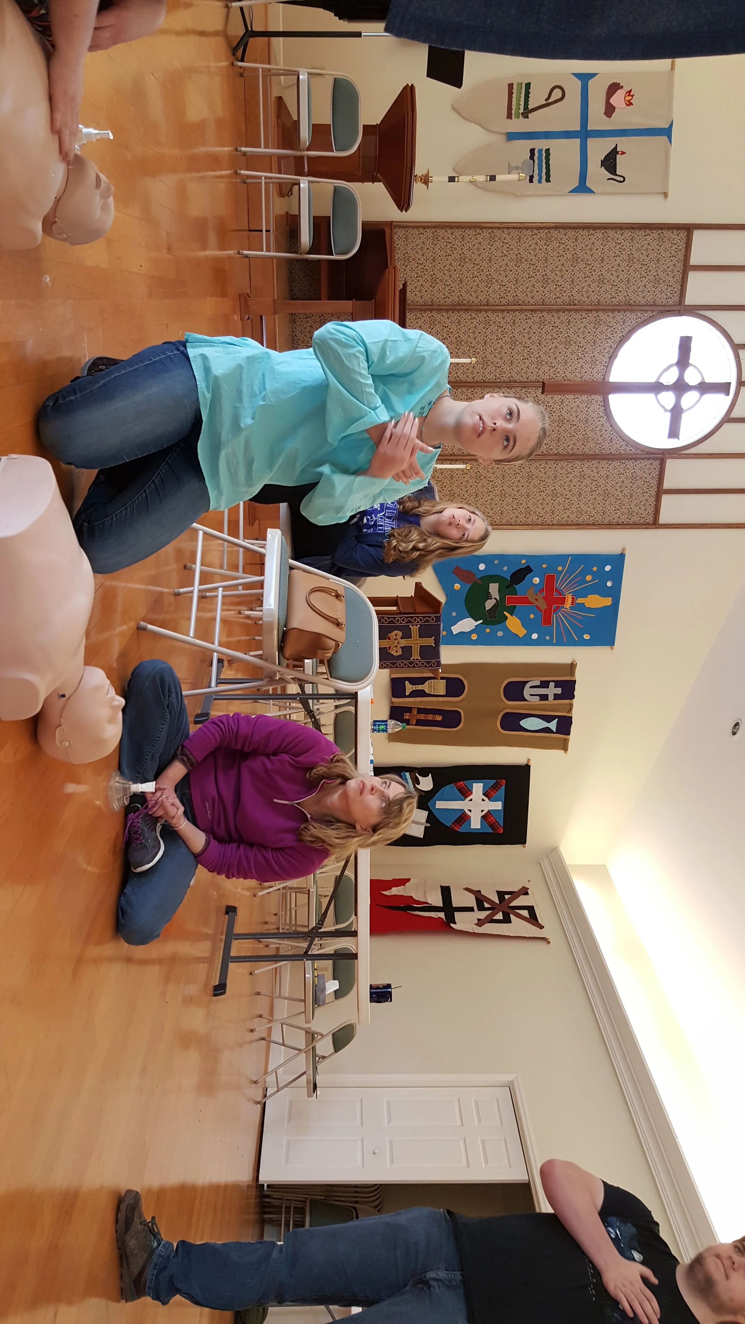 Group of people sitting on floor with CPR dummies in a room