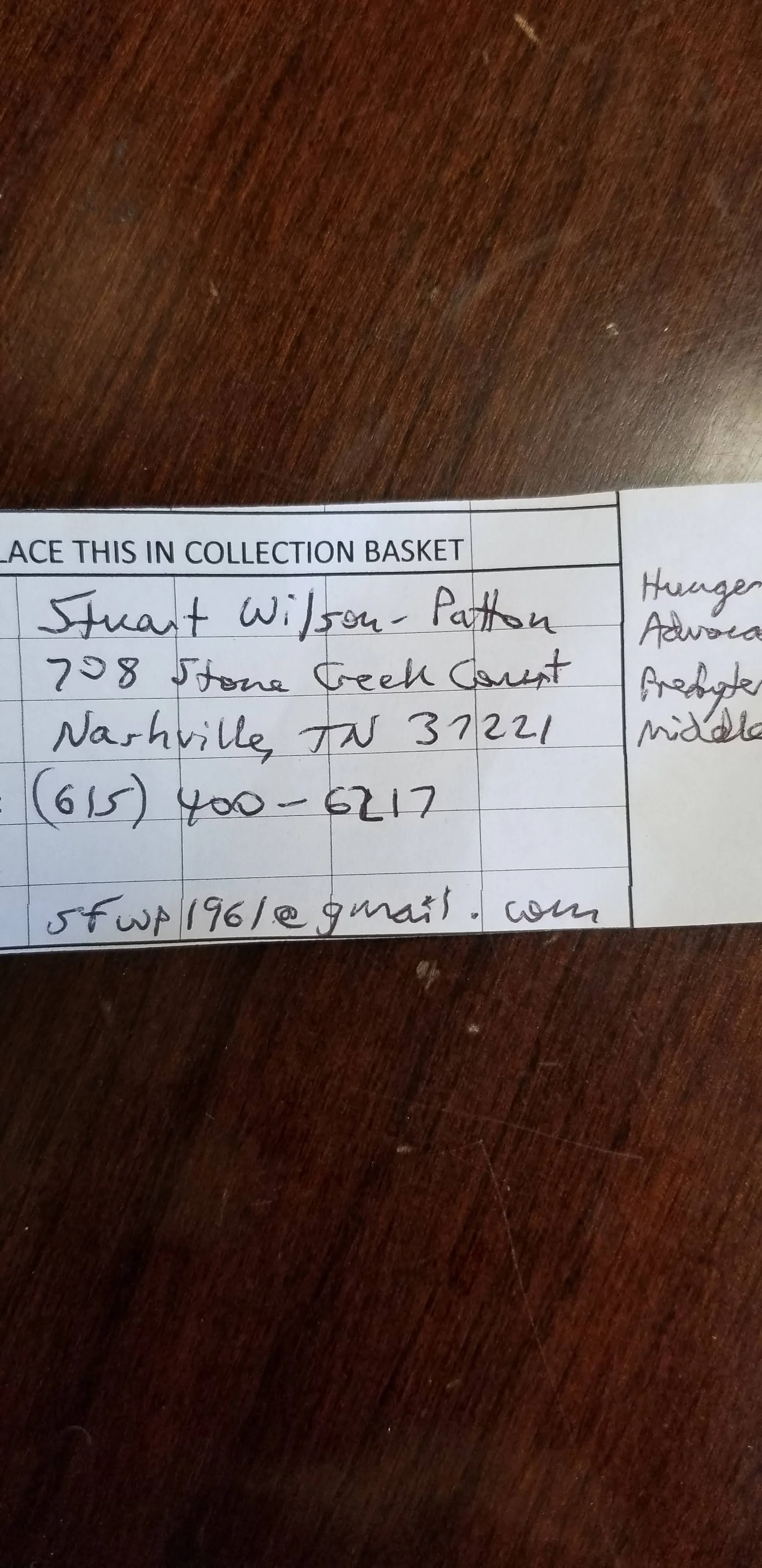 Handwritten form with personal contact information including name, address, phone number, and email, partially visible on a wooden table surface.