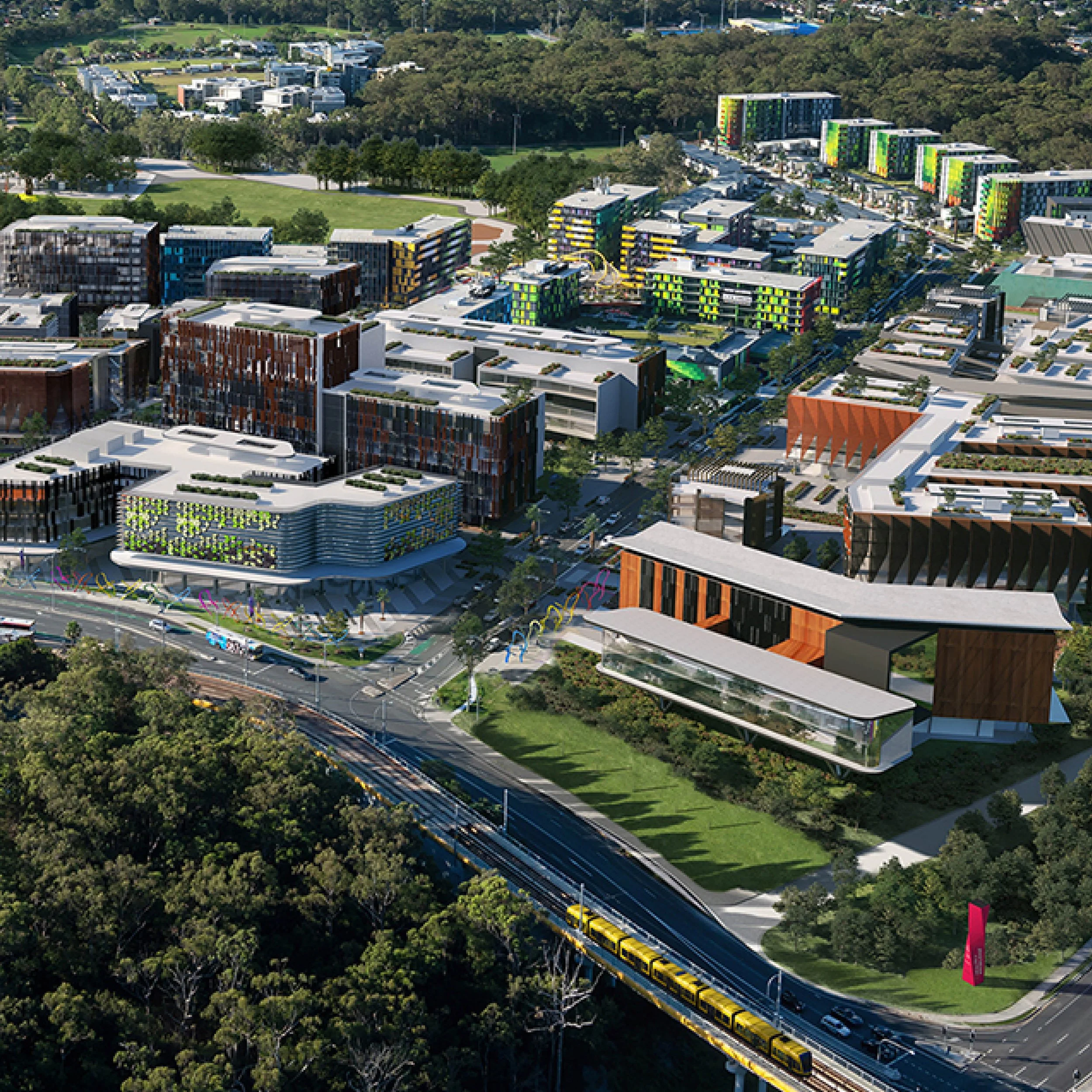 Aerial view of a modern urban development with colorful high-rise buildings, a train traveling on an elevated track, green parks, roads, and surrounding trees.