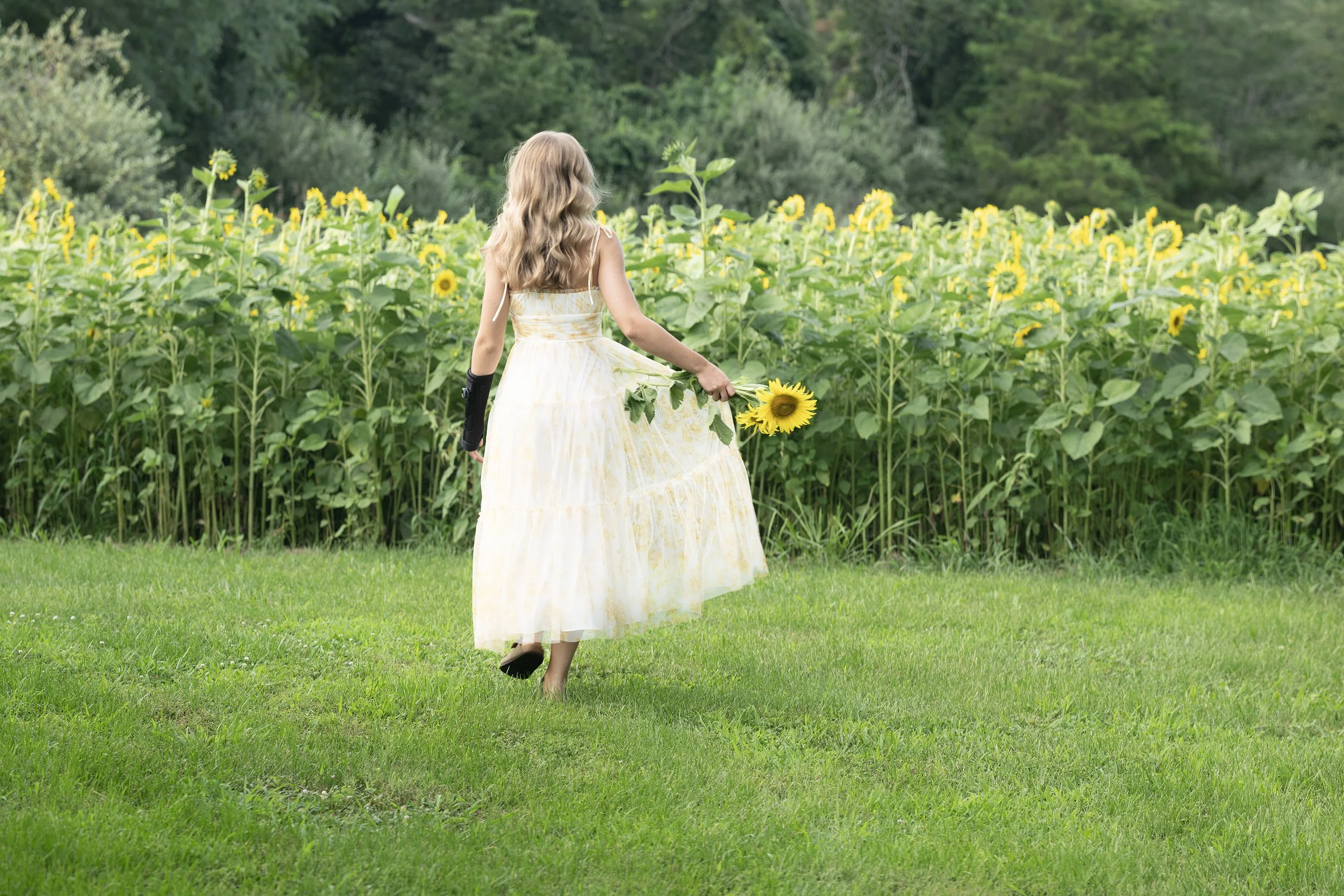 Class of 2027 Senior Girl walking towards a field of Sunflowers in Marion Southern Illinois